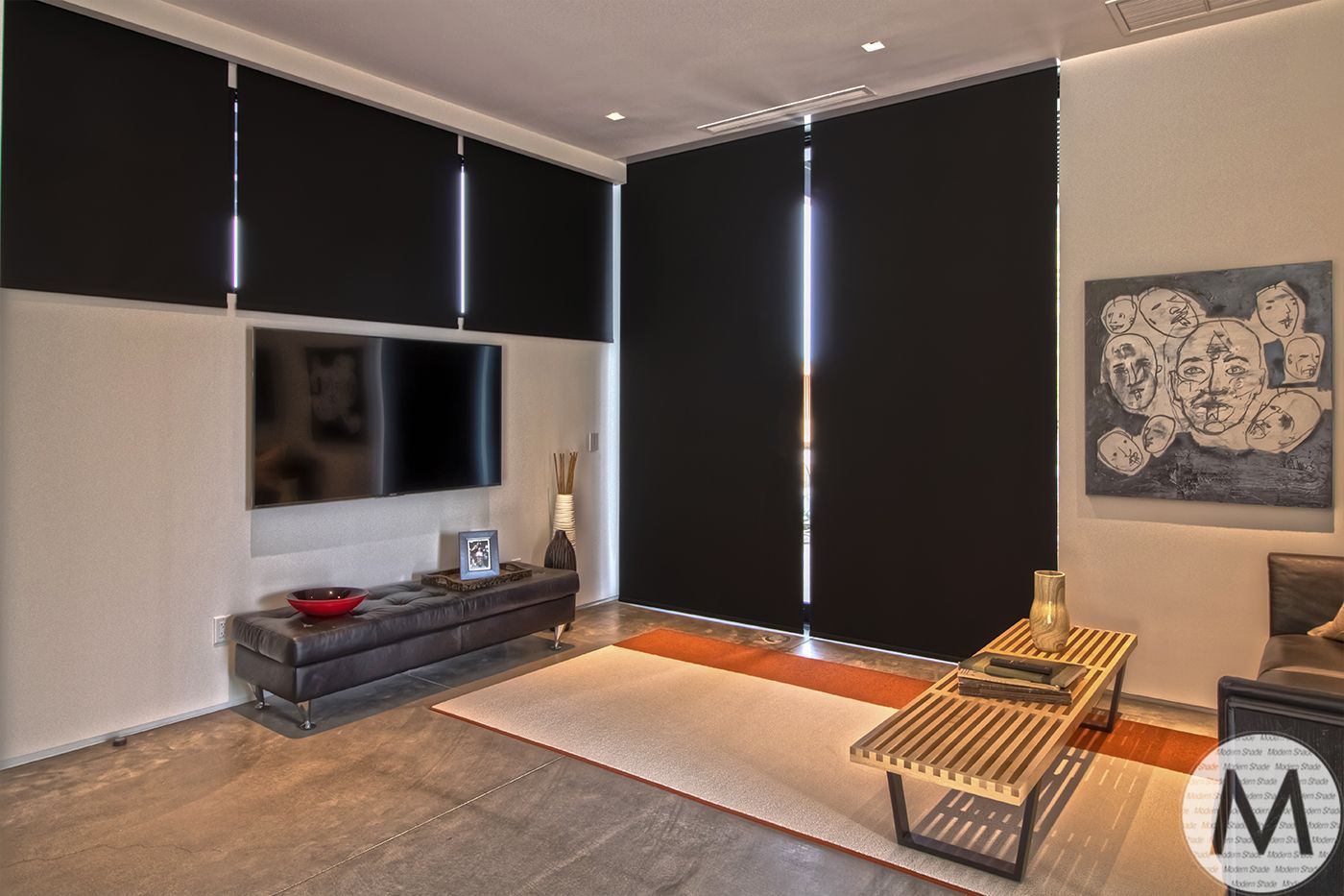 Modern living room with black blinds, TV, artwork, and wood and leather furniture.