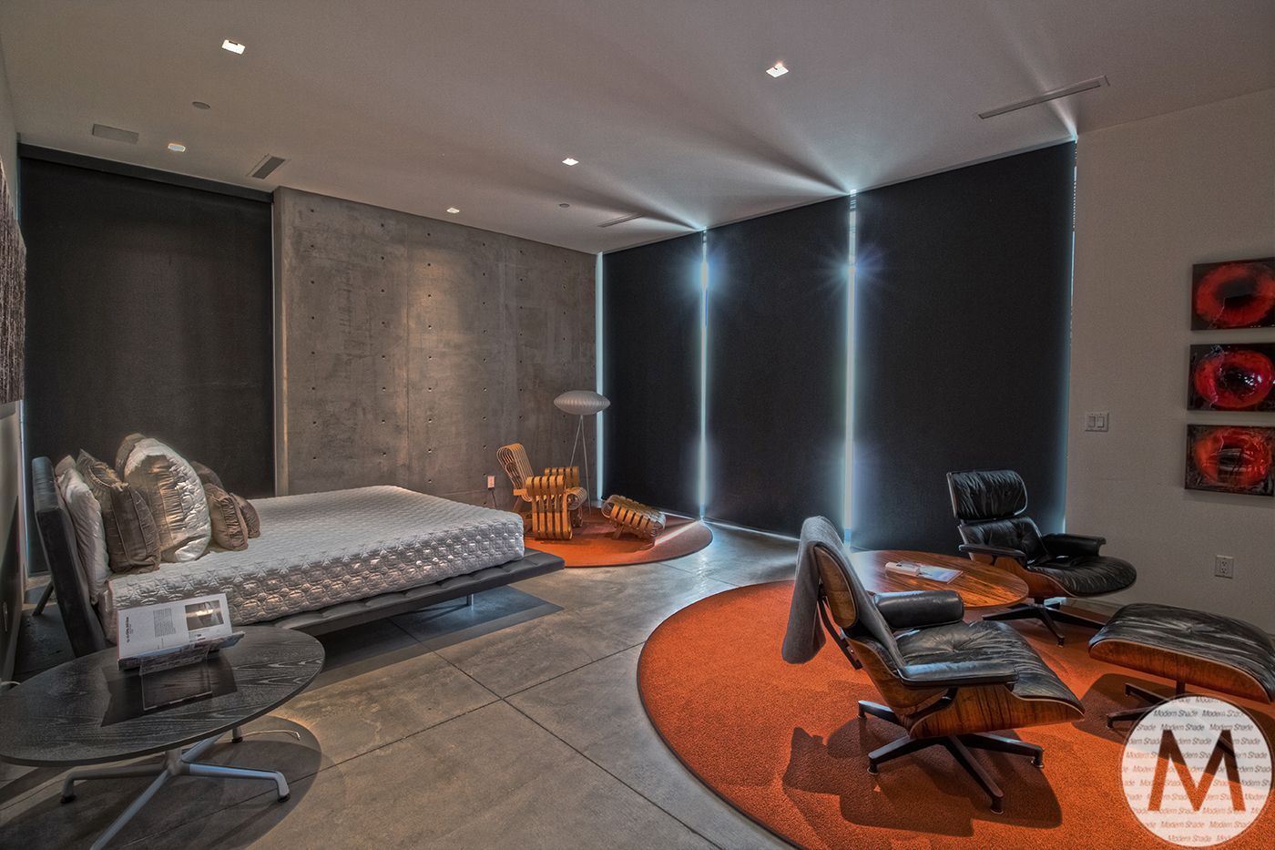 Modern bedroom with orange rug, gray concrete walls, black accent wall with light strips, and a bed.