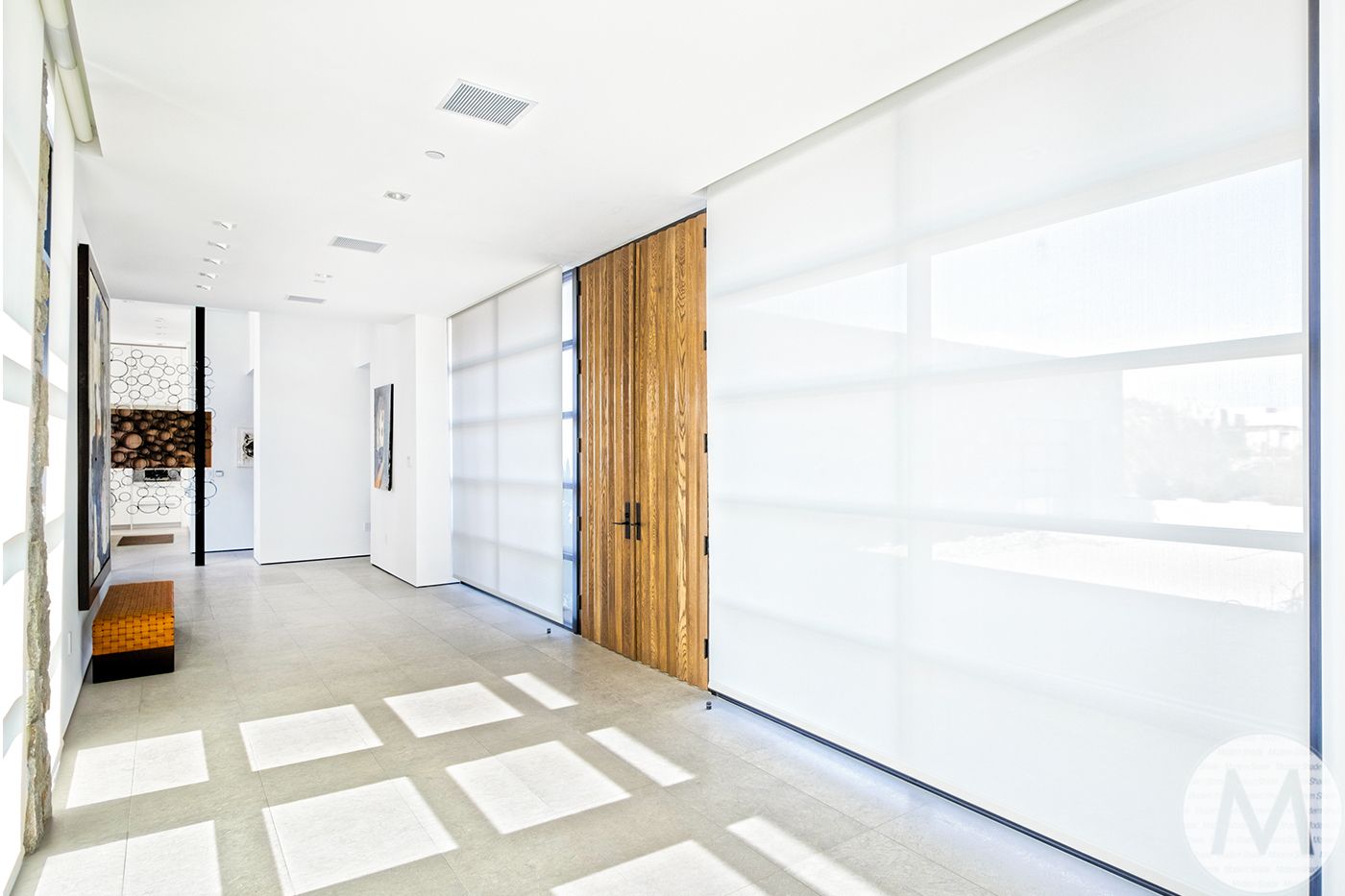 Bright hallway with white walls, large white window panels, and a wooden door.