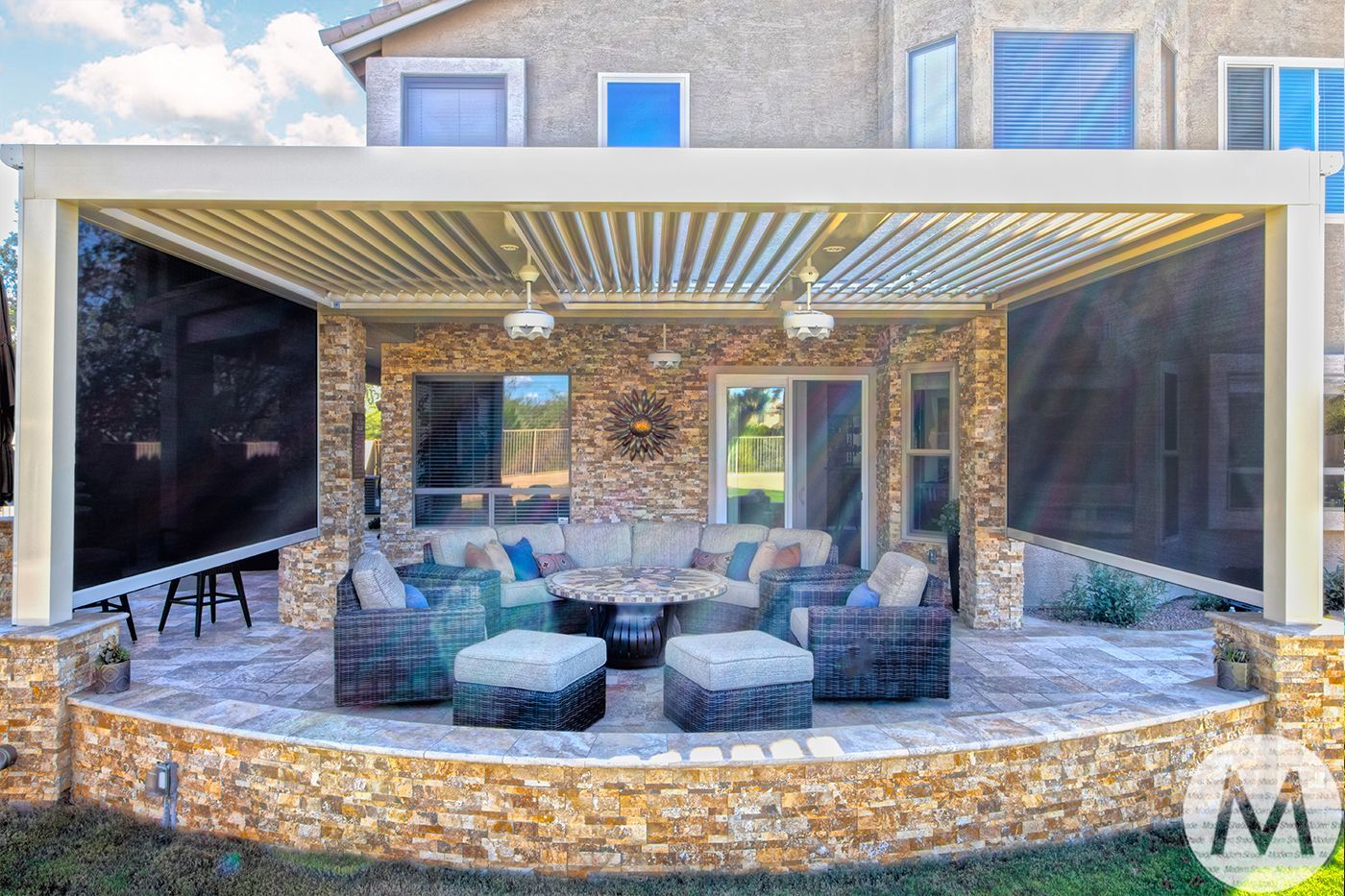 Outdoor patio with lounge furniture, stone wall, retractable screens, and overhead shade.