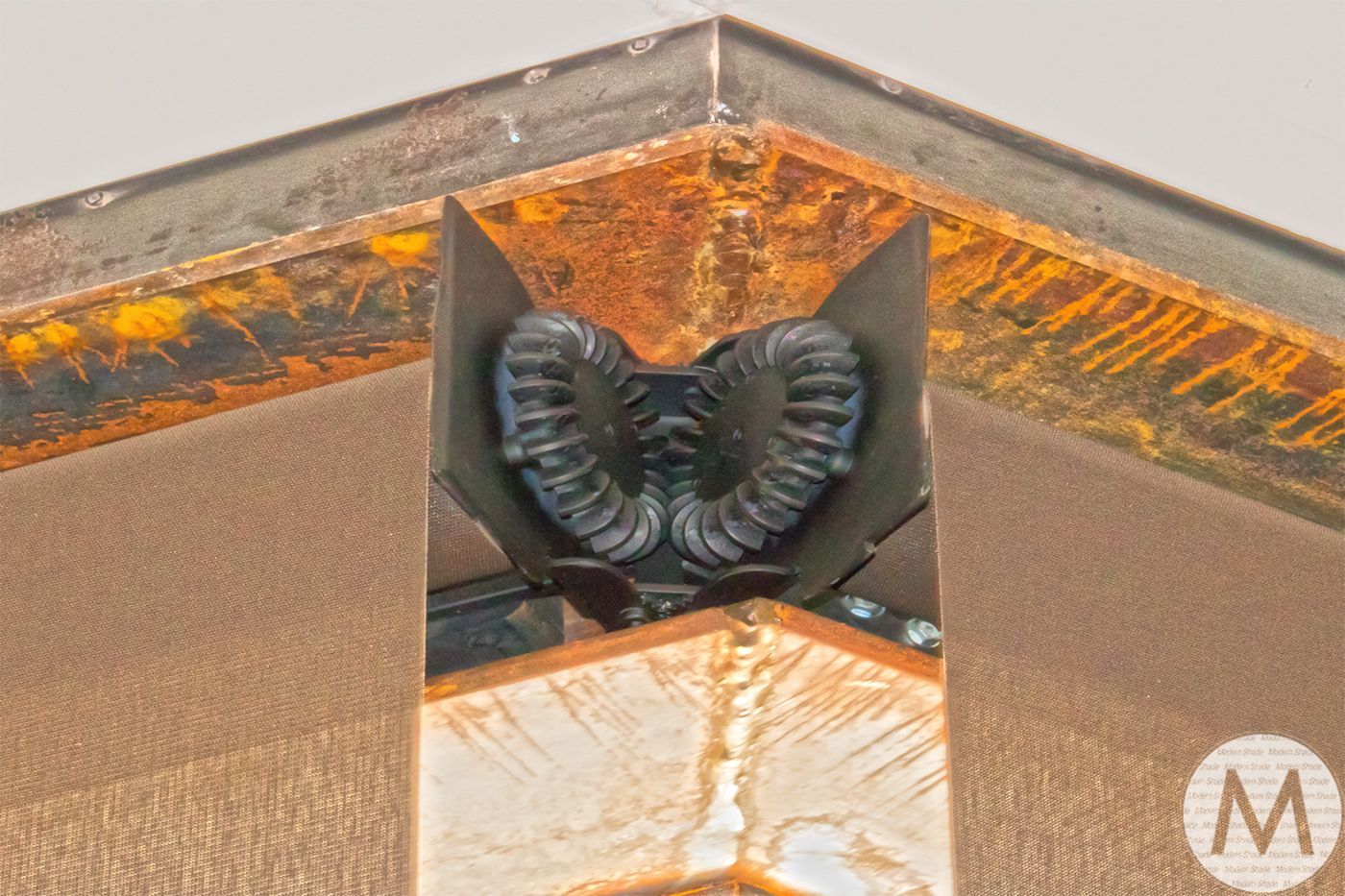 Corner detail with rusty metal trim, a black ram sculpture, and tan-colored walls.