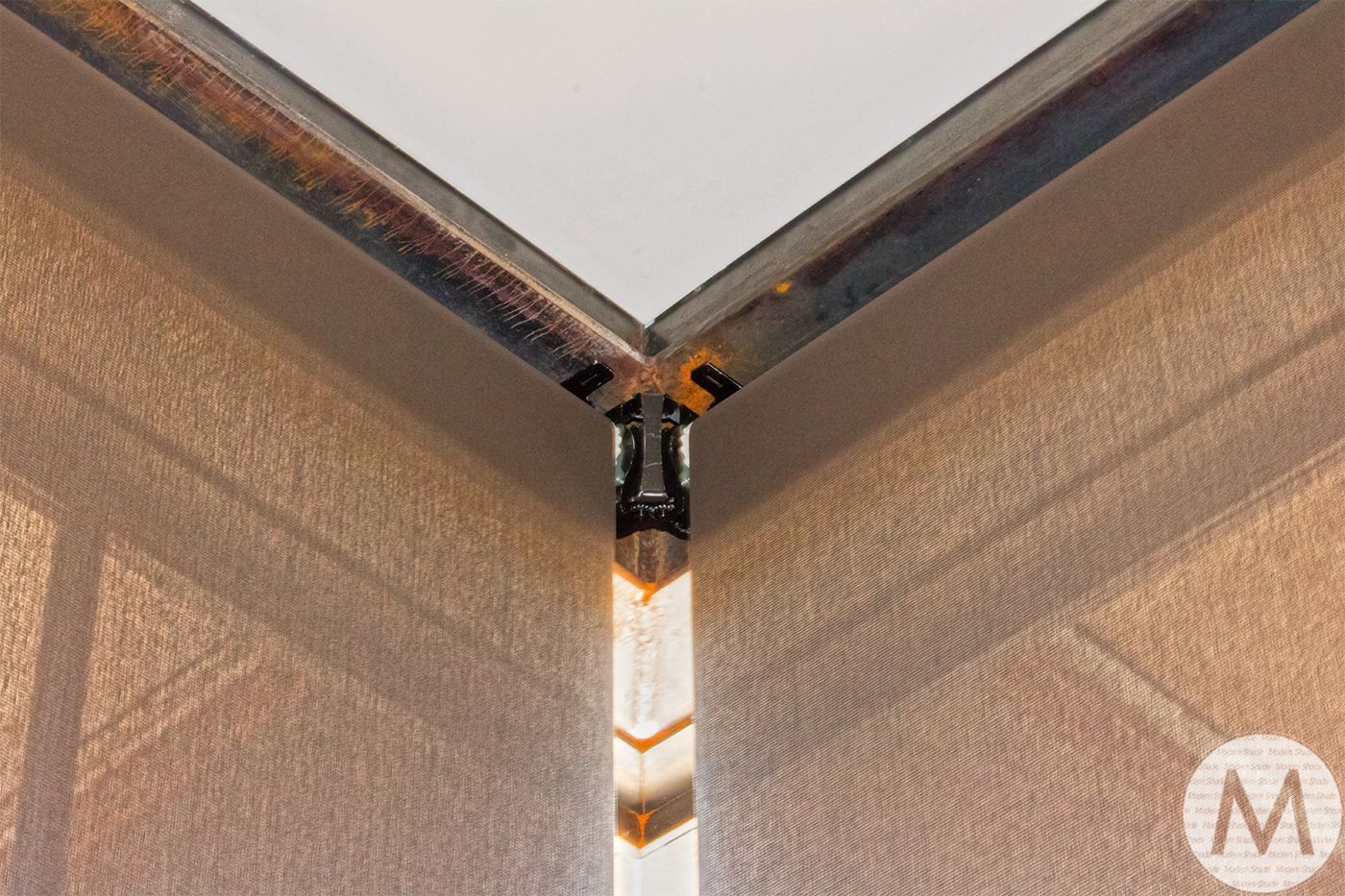 Corner view of a brown screen, with a metal frame, and white ceiling.