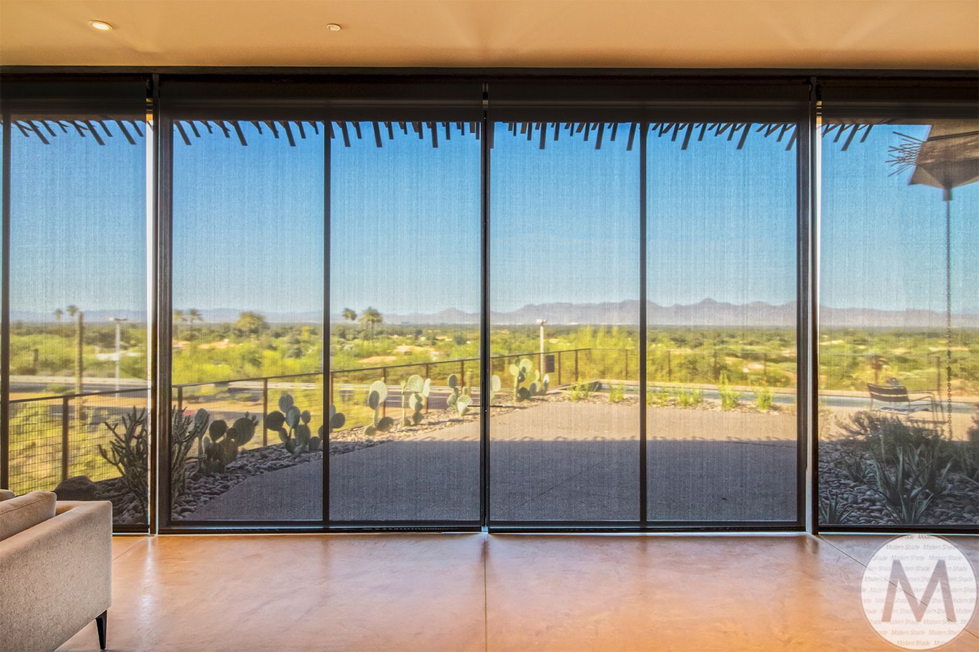 Large windows with desert view, shaded by black patterned blinds.