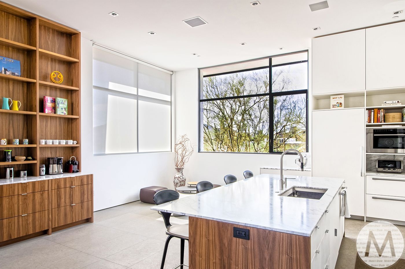 Modern kitchen with wooden cabinets, white walls, and large windows.