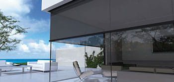 Modern home with retractable shades, glass walls, and ocean view.