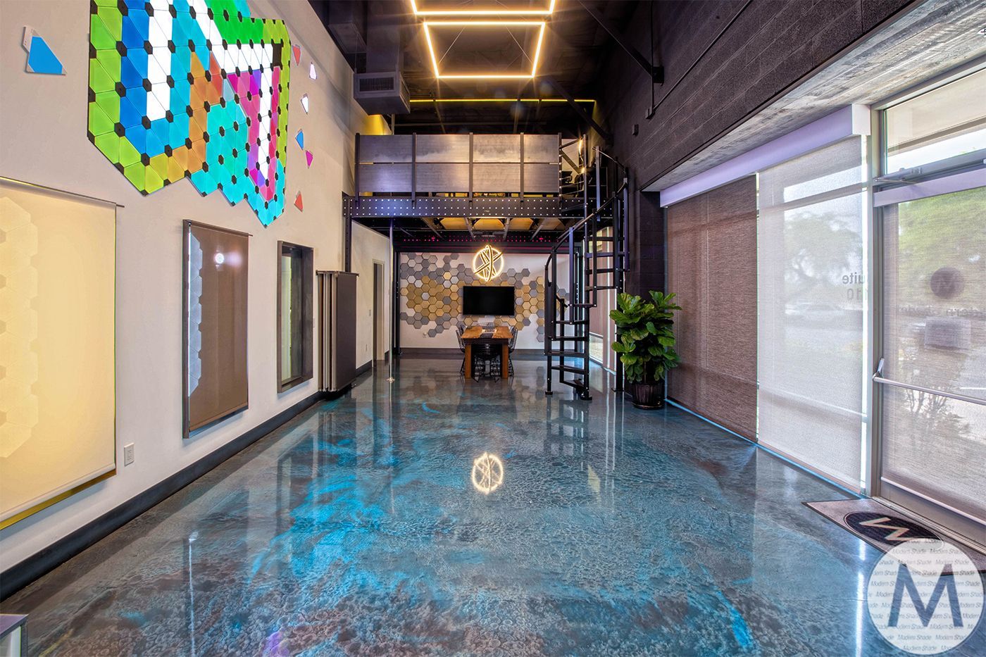 Modern office space with loft, art, and shiny blue floor.