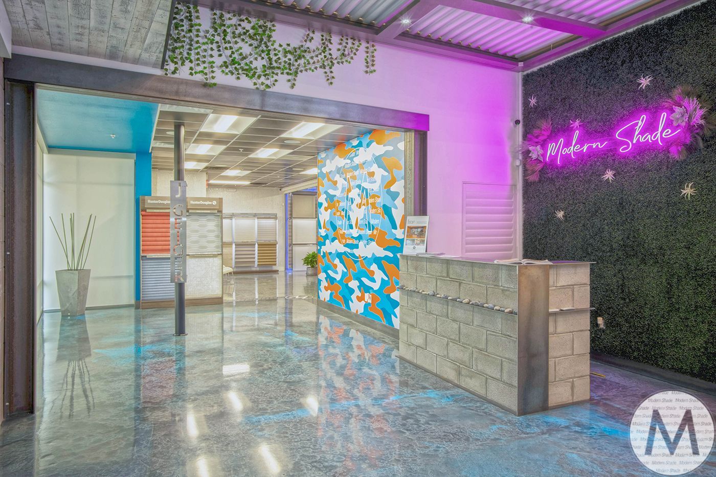 Interior design showroom with a reception desk, colorful wall art, and neon sign.