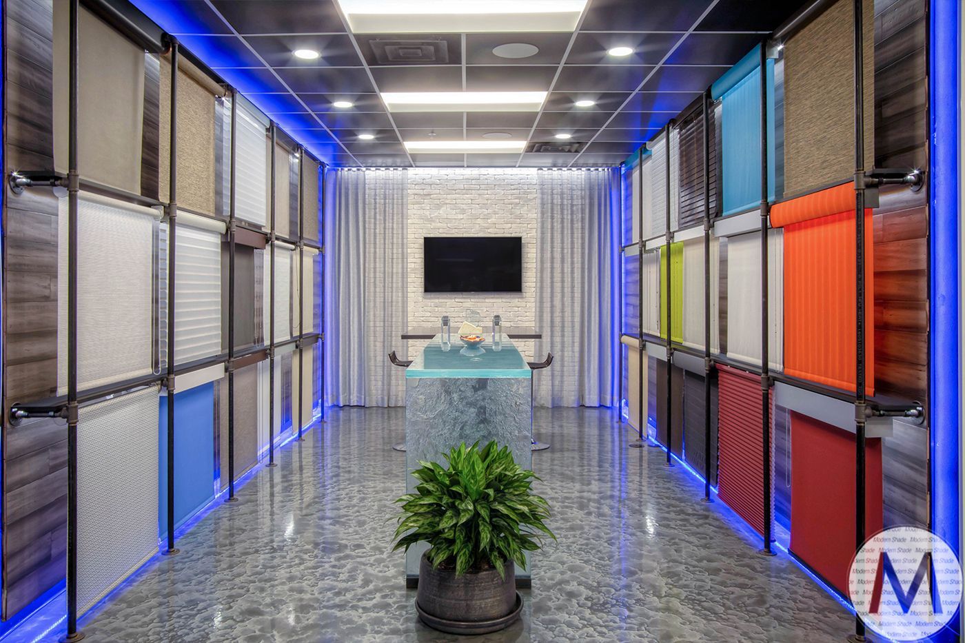 Interior showroom with various colored window blinds displayed on walls, with a central seating area.
