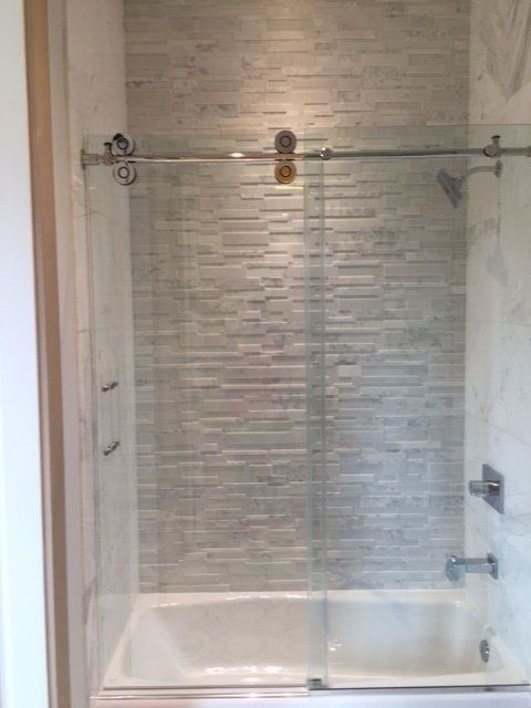 A bathroom with a bathtub and a shower with a sliding glass door.