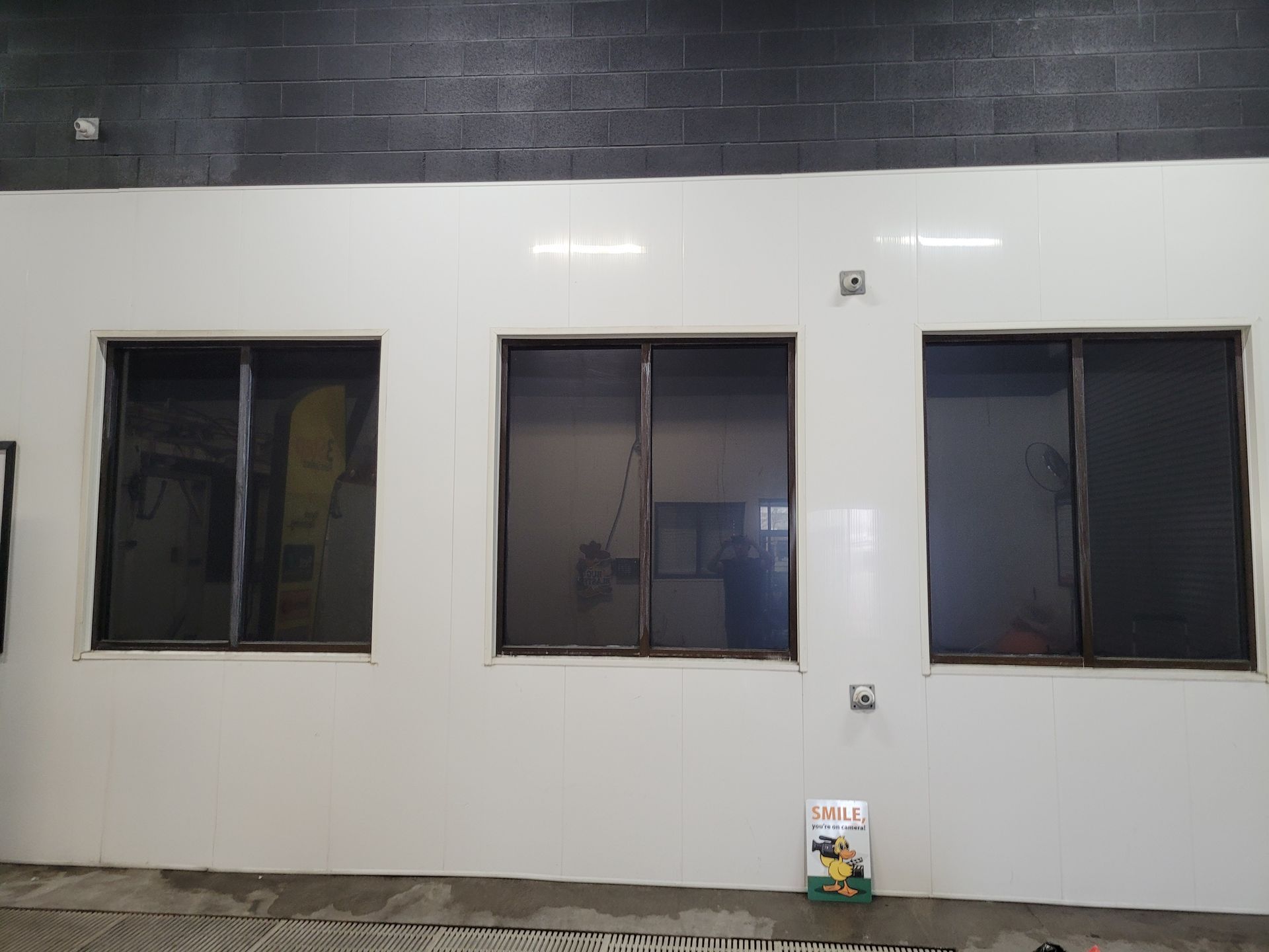 Three dark-tinted windows set in a white wall. A book rests on the floor below the center window.