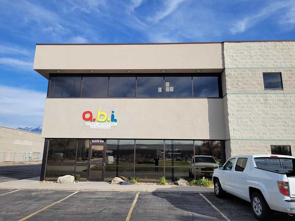 Exterior of a beige two-story building with large windows. The sign on the building reads 