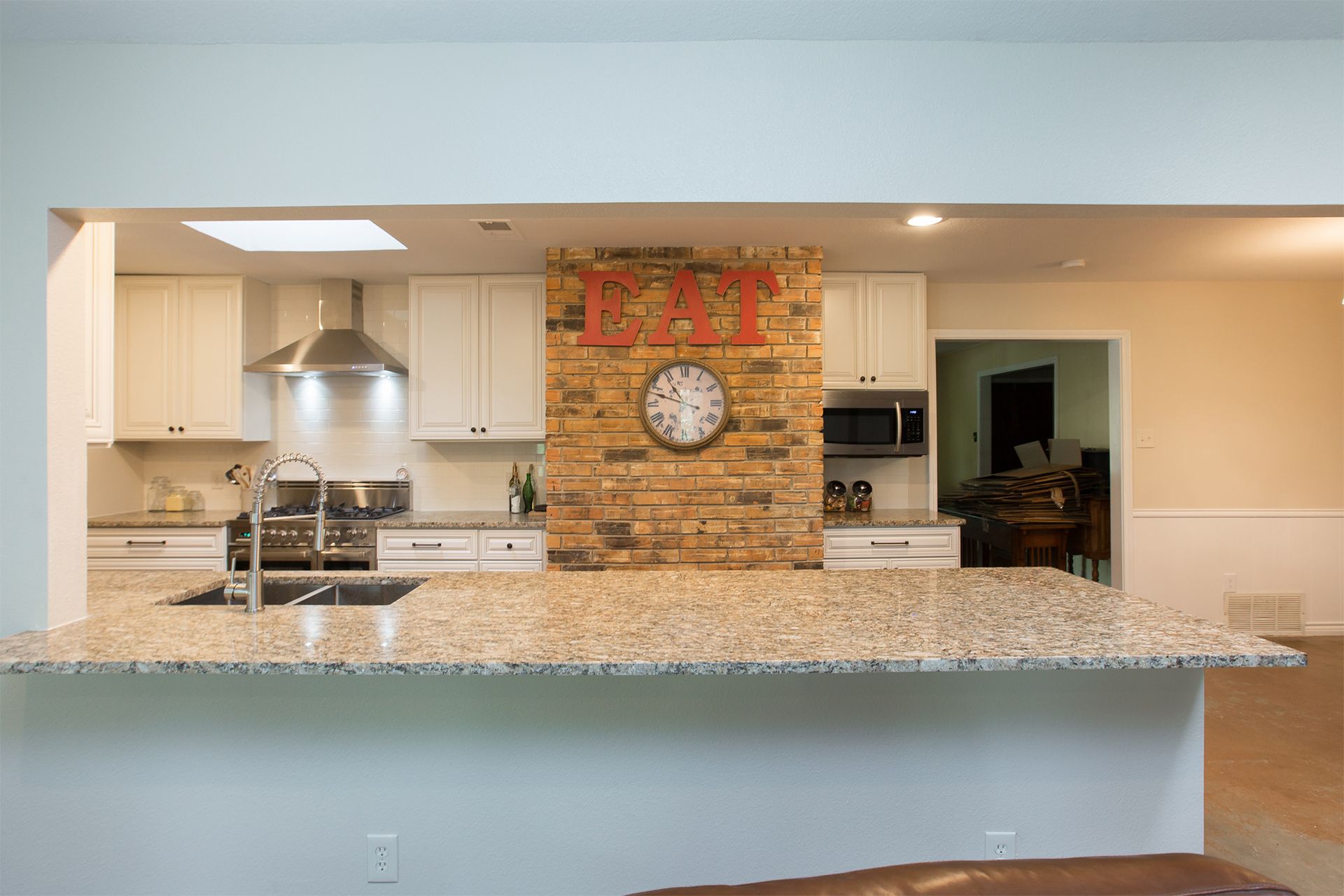 Kitchen with white cabinets, brick accent wall with 