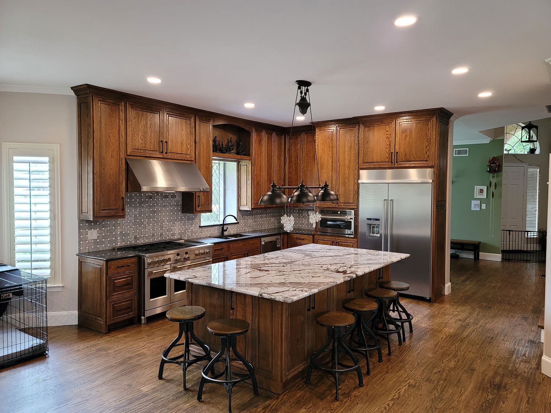 White kitchen cabinets with stone backsplash, stainless steel sink, and dark wood floors. - After