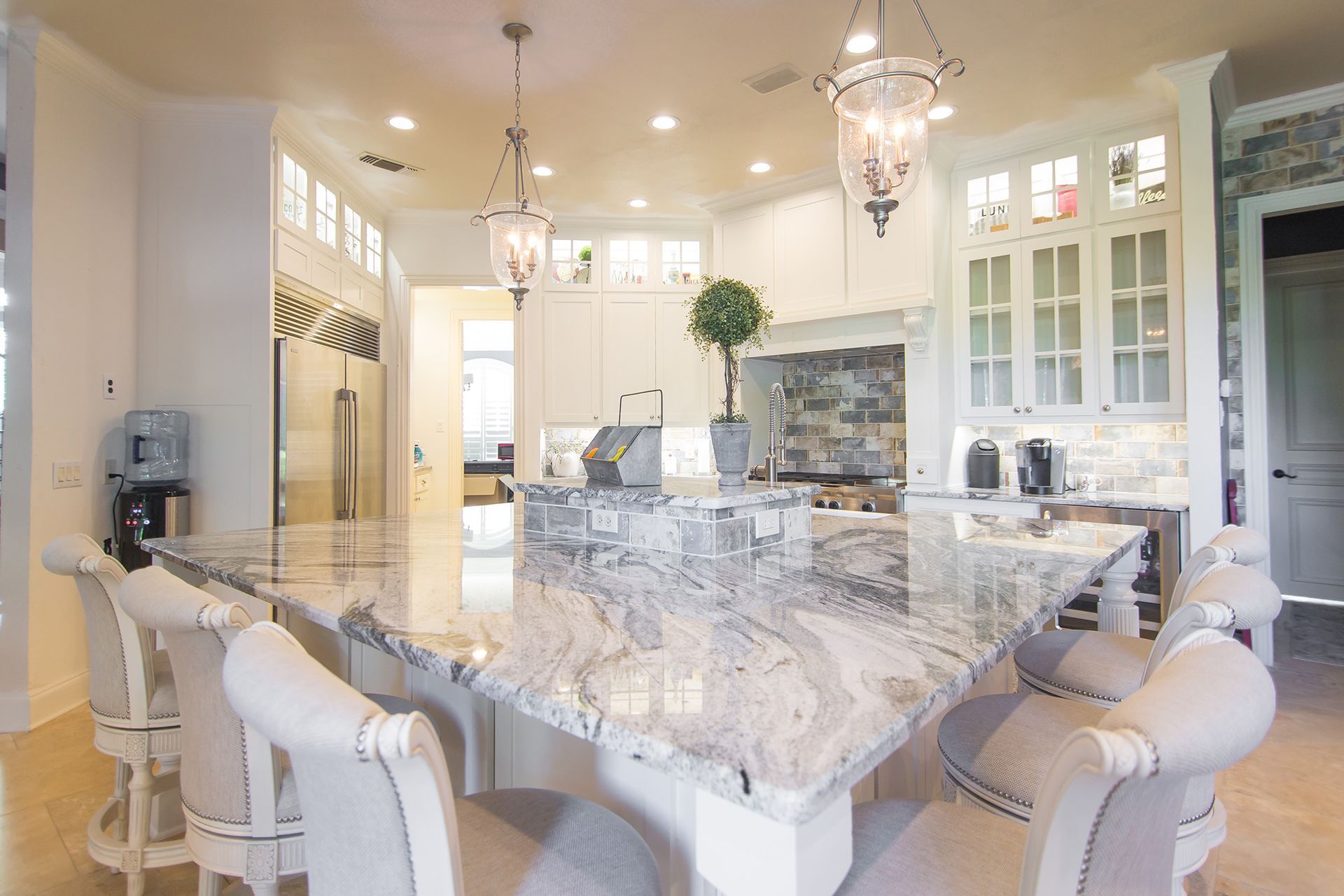 Elegant white kitchen with large marble island and seating. - After