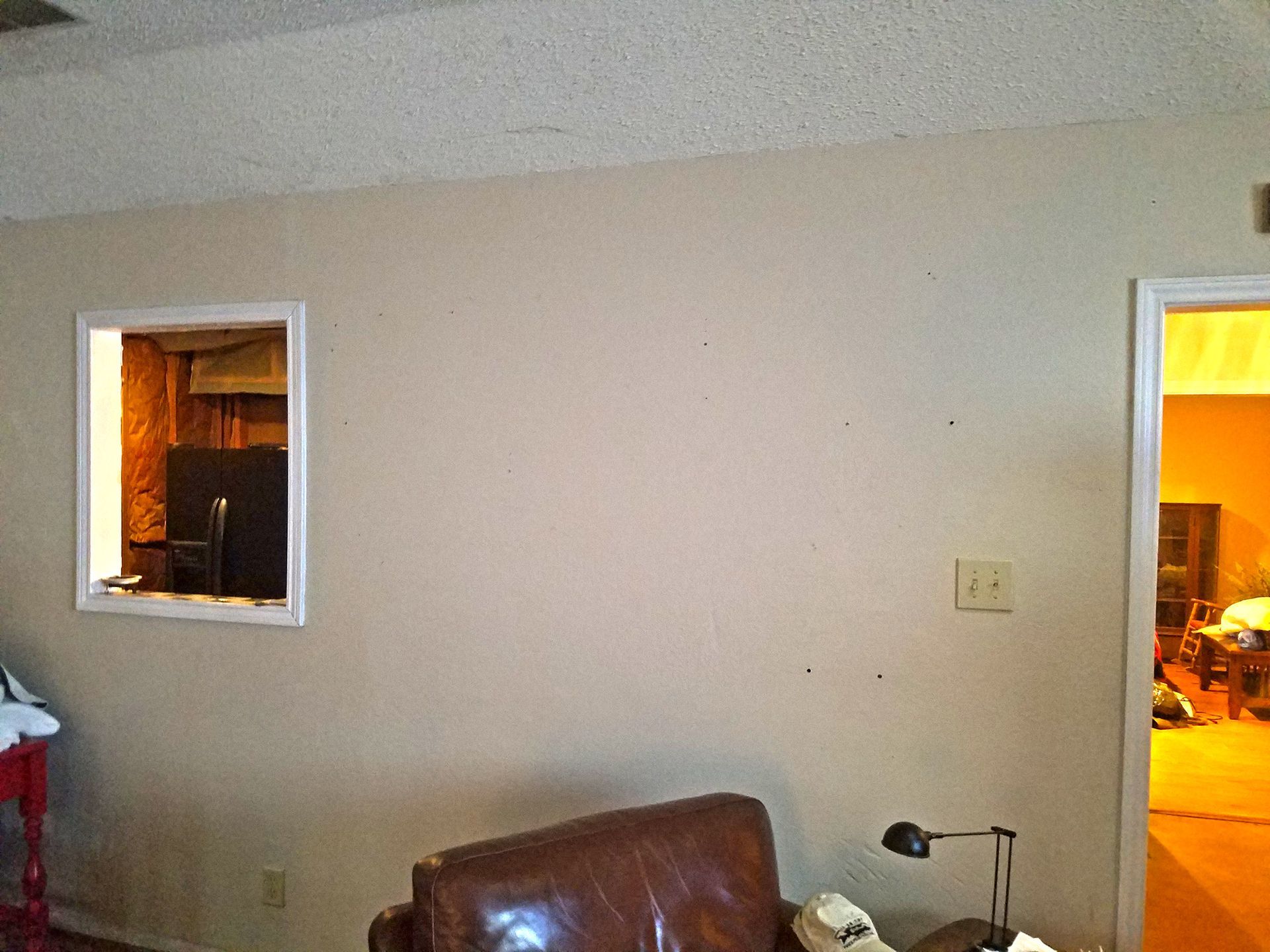 Room interior with a window, door, brown leather chair, and beige walls. - Before