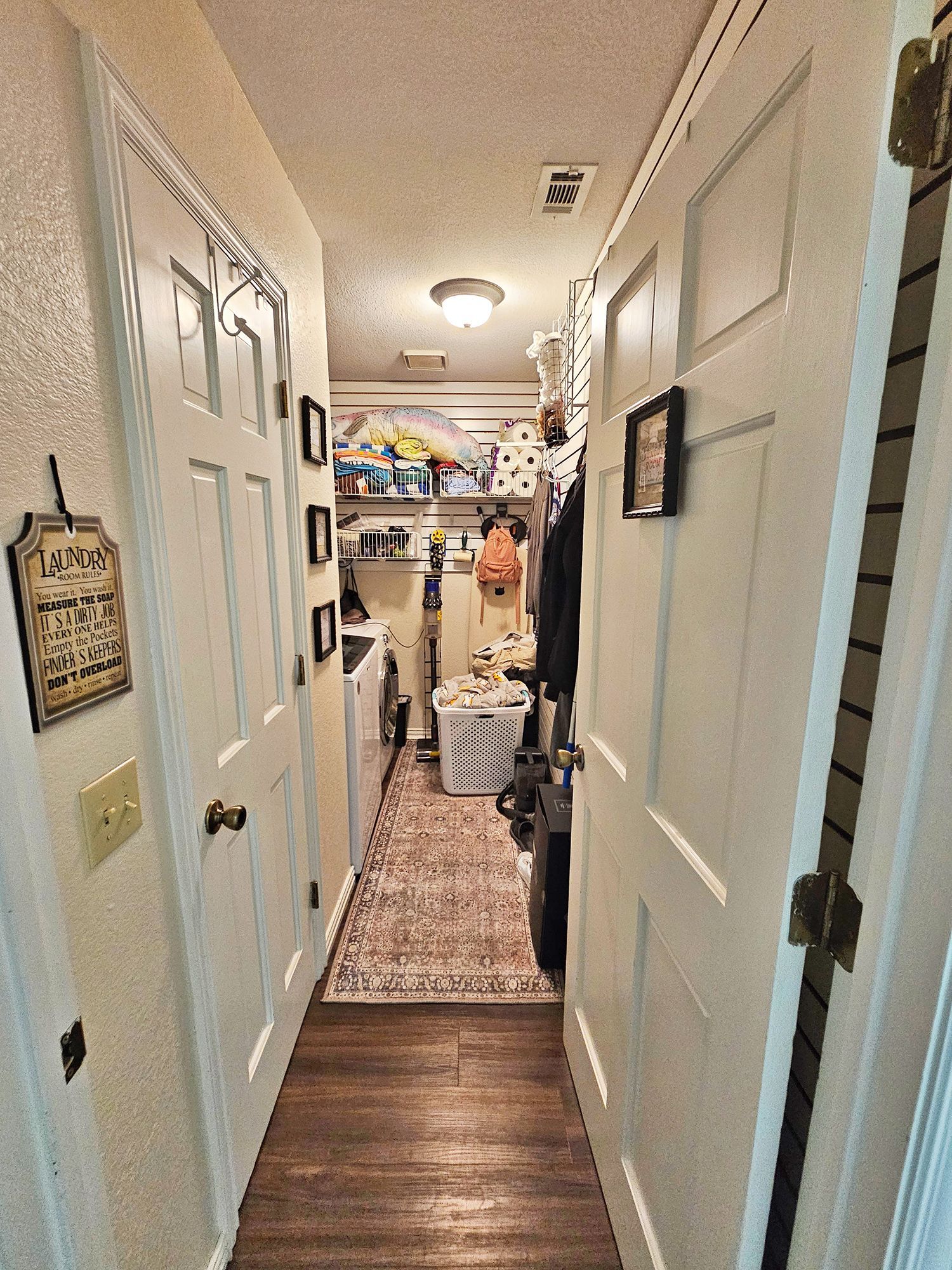 Laundry room with white doors, washer, dryer, rug, and shelves. - Before