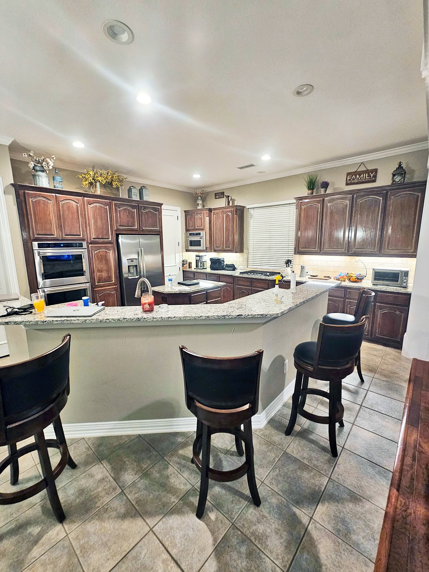 Kitchen with dark brown cabinets, stainless steel appliances, and bar seating. - Before