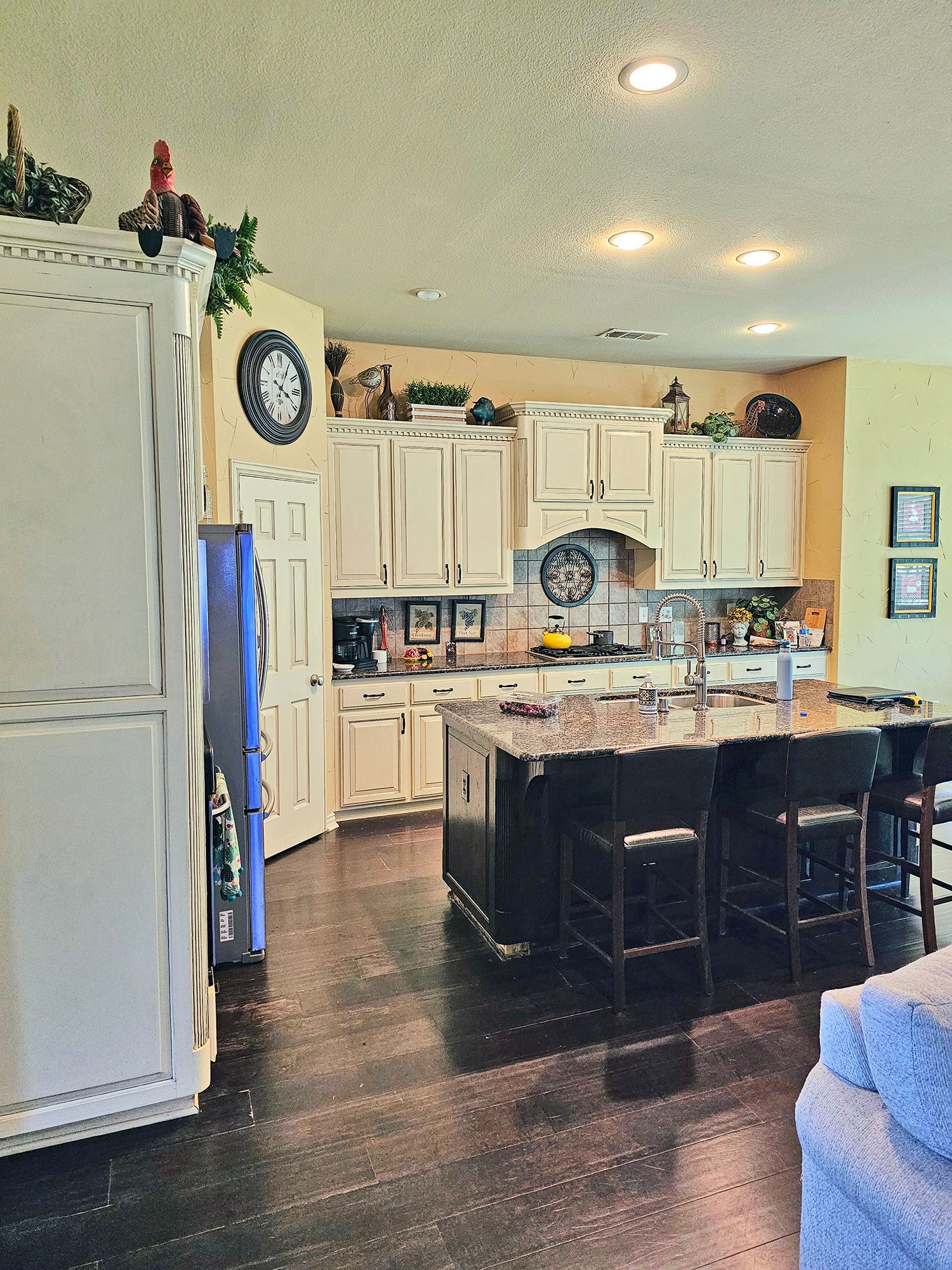Kitchen with cream cabinets, dark island, and hardwood floors. - Before