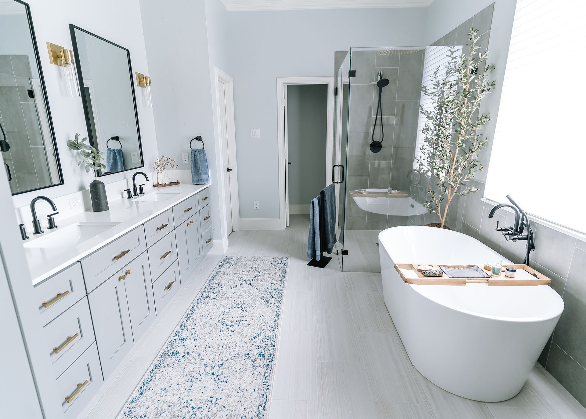 Spacious, modern bathroom with a white freestanding tub, double sinks, and gray accents.