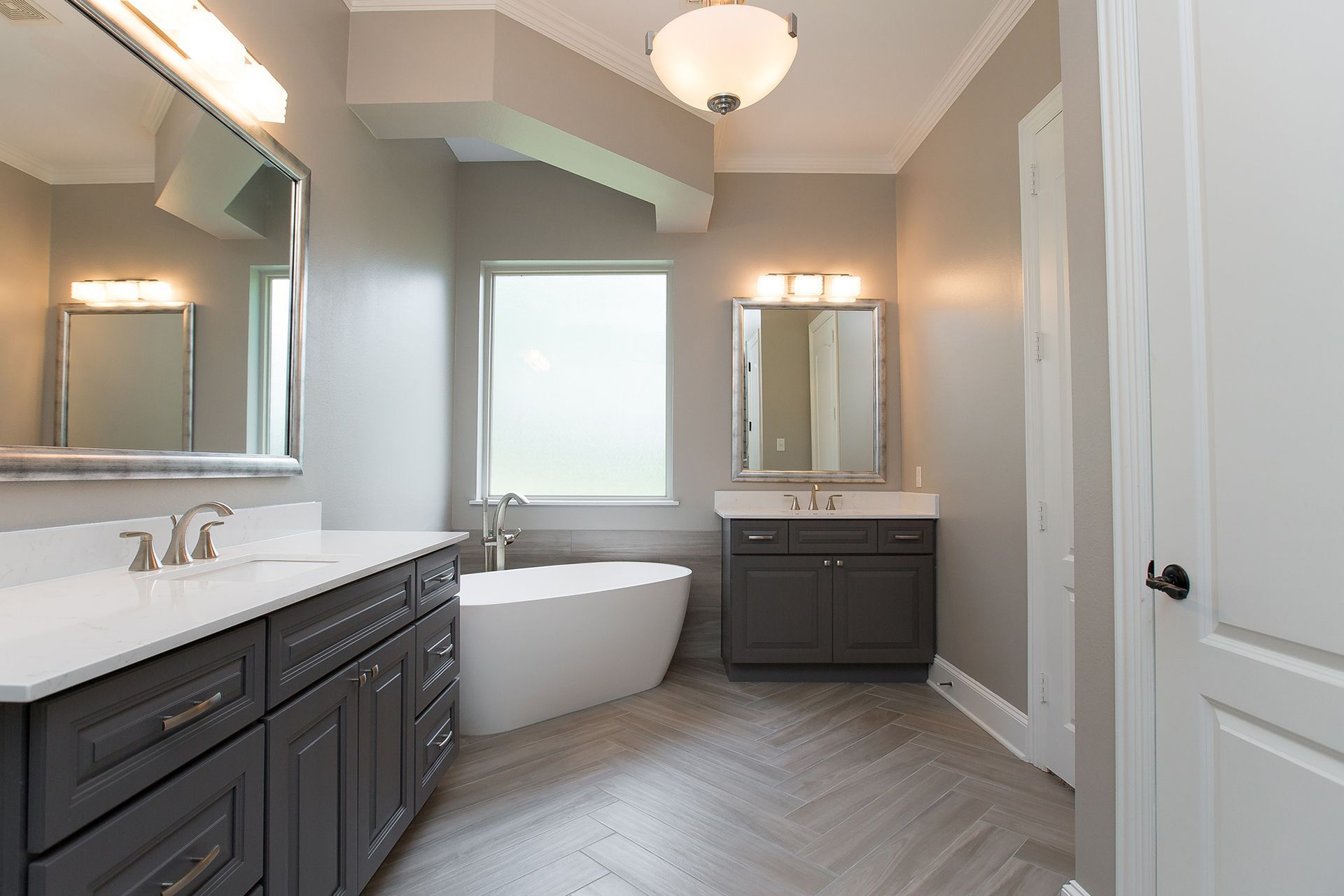 Modern bathroom with gray cabinets, white tub, and light gray walls.