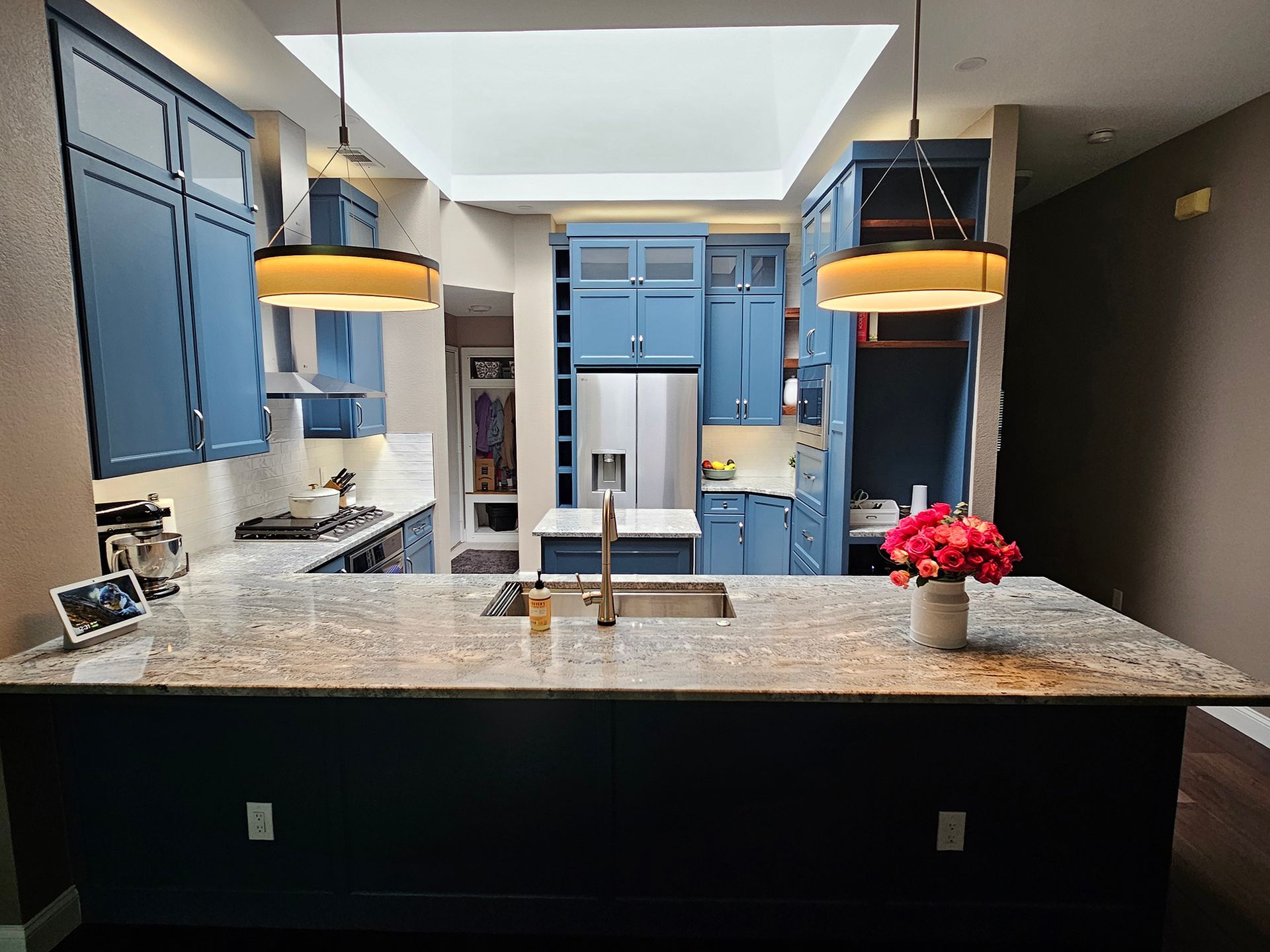 Blue kitchen with island, granite countertop, and pendant lights.
