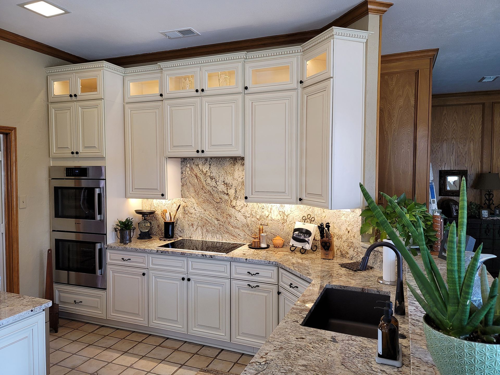 Cream-colored kitchen cabinets with a granite countertop, a black sink, and a built-in microwave/oven.