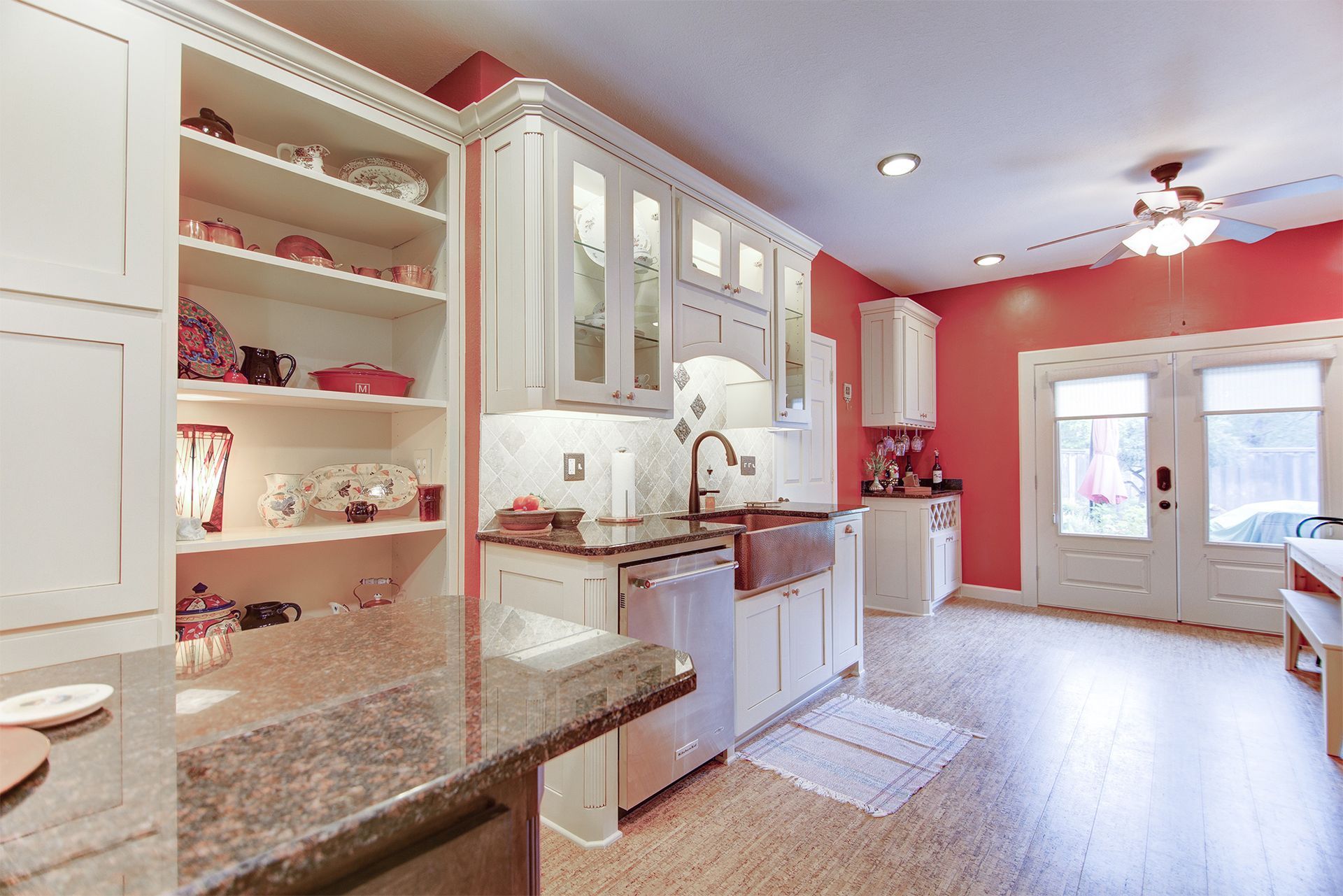 White kitchen with open shelving, red walls, and a door to the outside.
