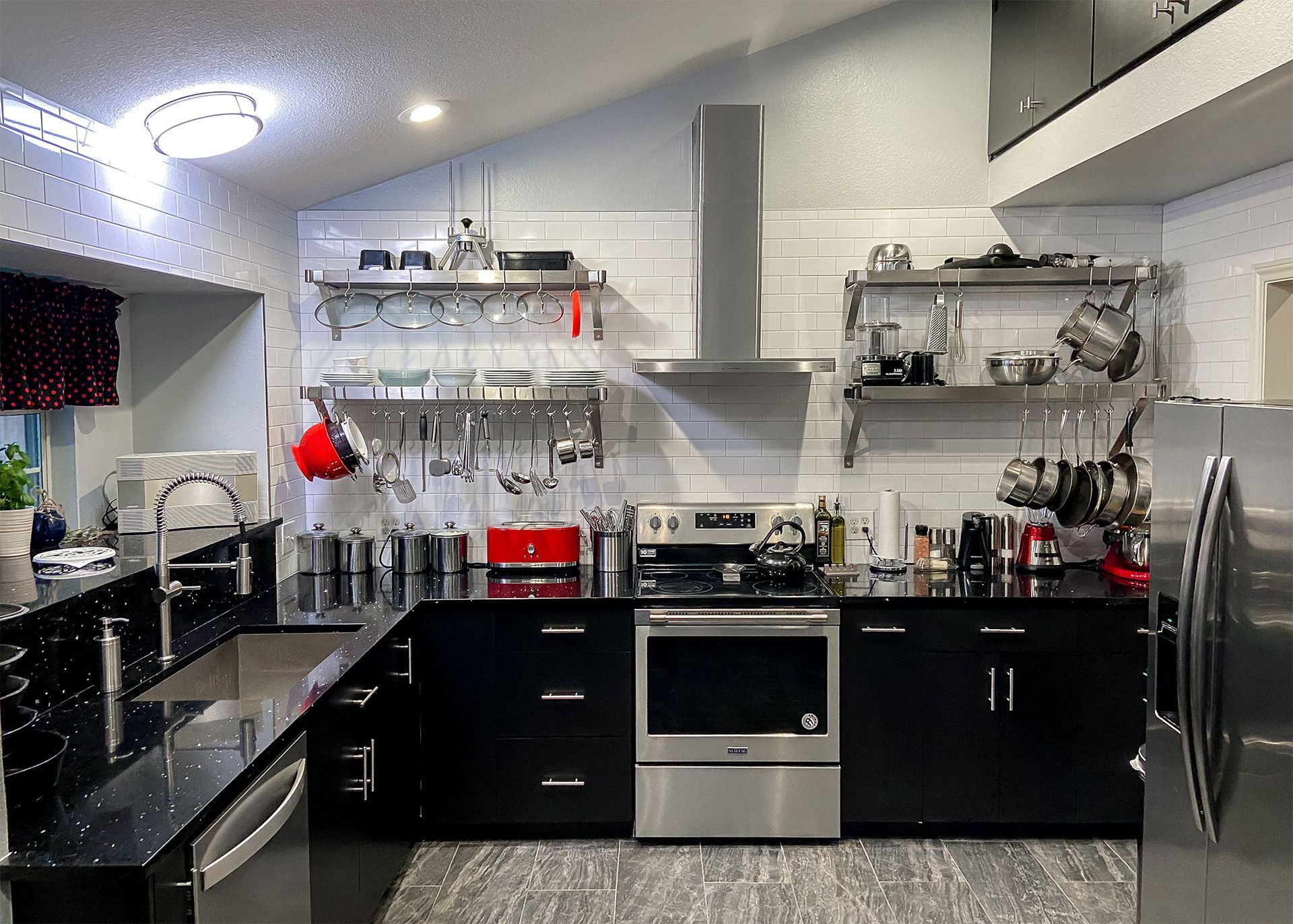 Modern kitchen with black cabinets, stainless steel appliances, and open shelving.