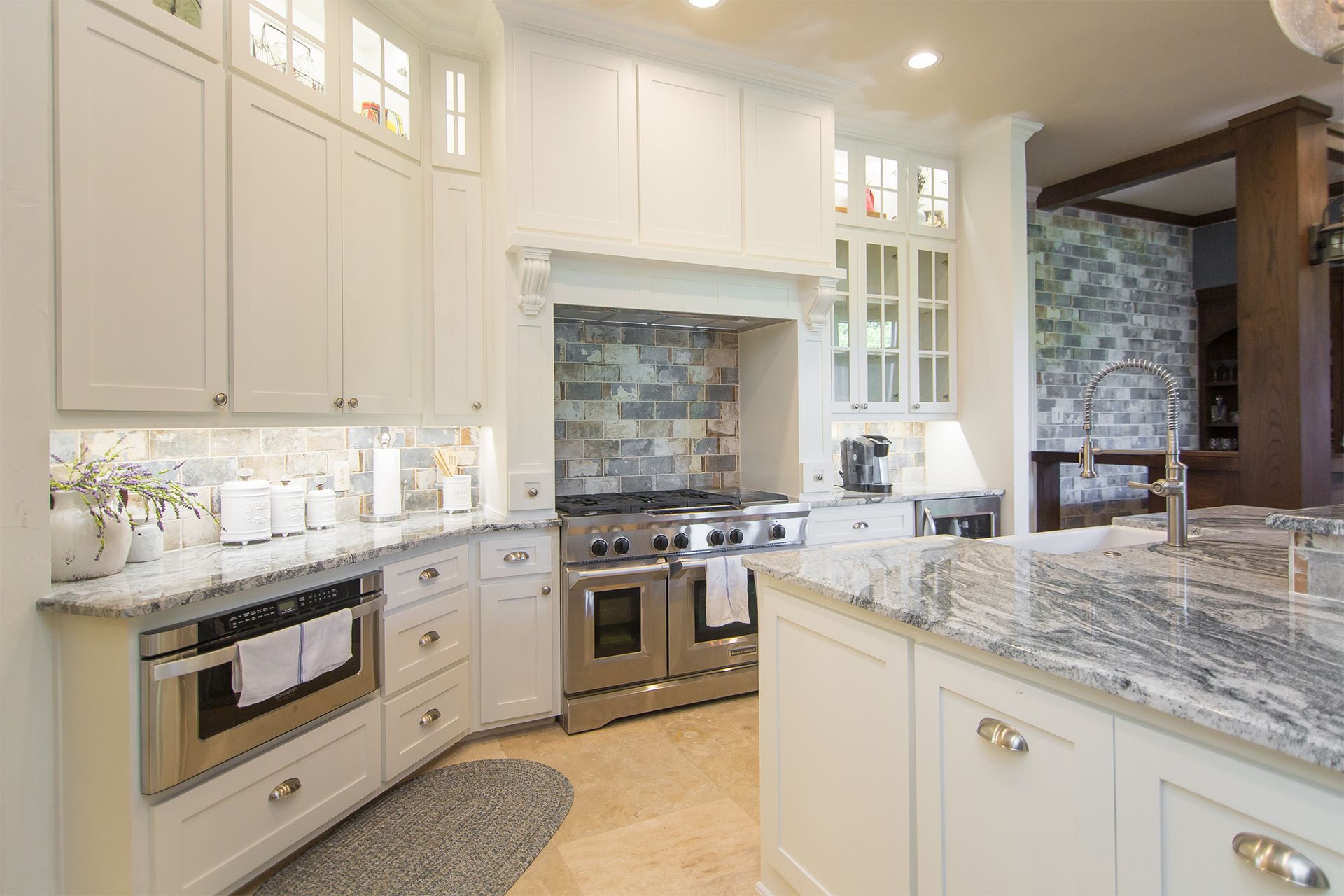 White kitchen with stainless steel appliances, granite countertops, and a stone backsplash.