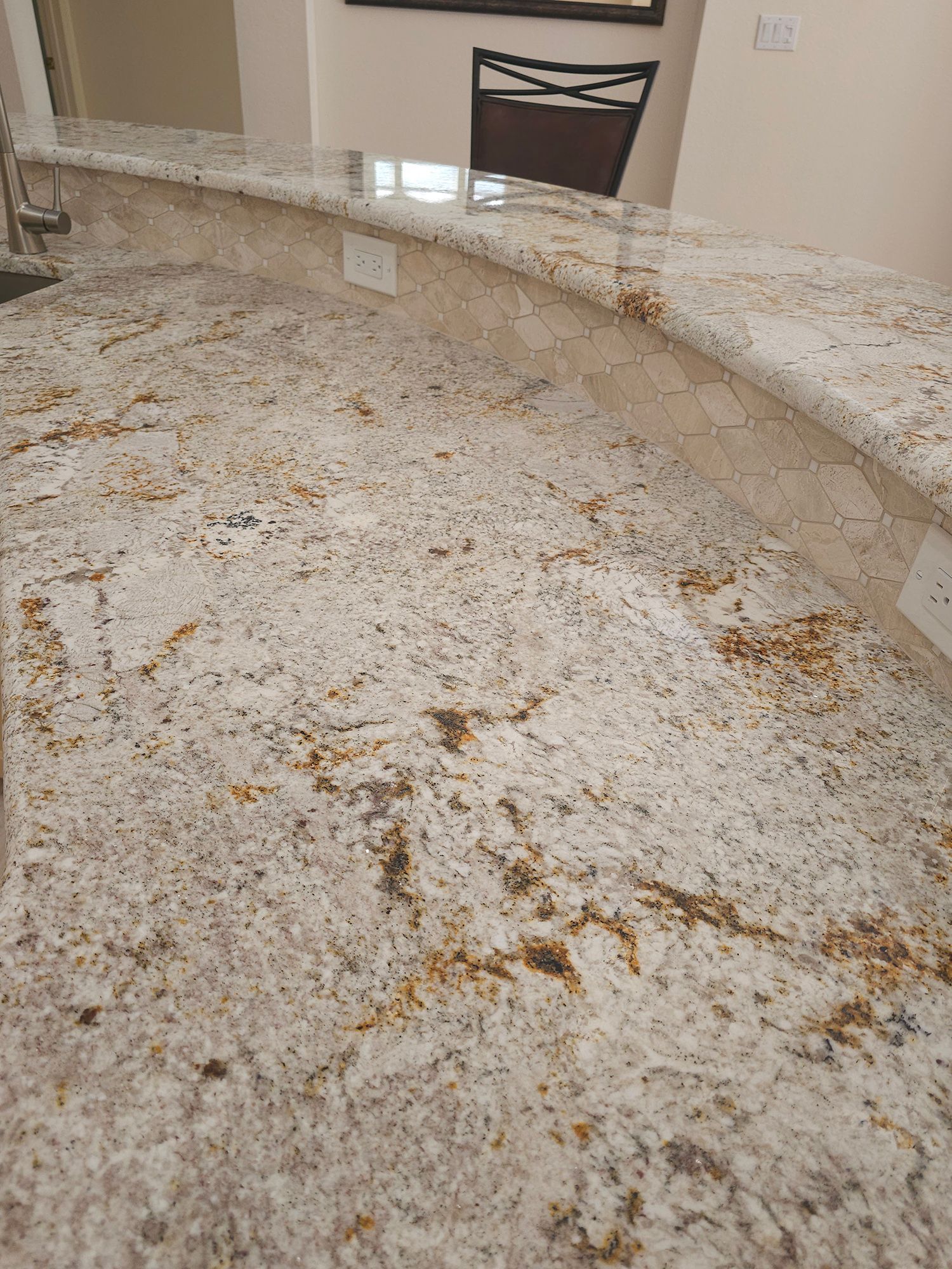 Granite countertop with beige, white, and gold swirls, with electrical outlets along the edge.