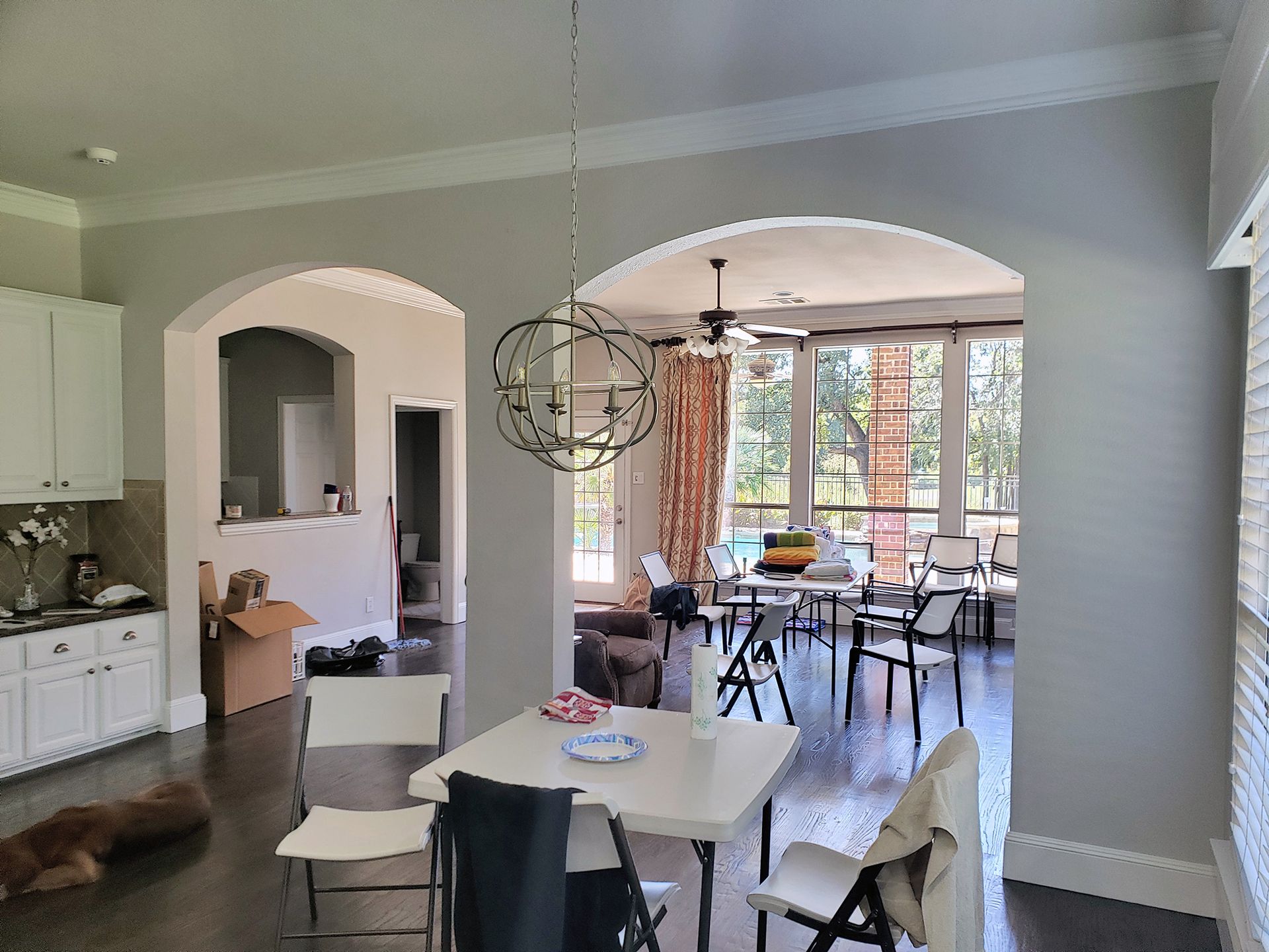 Kitchen and dining area with archways, a chandelier, and sunlight streaming through windows.