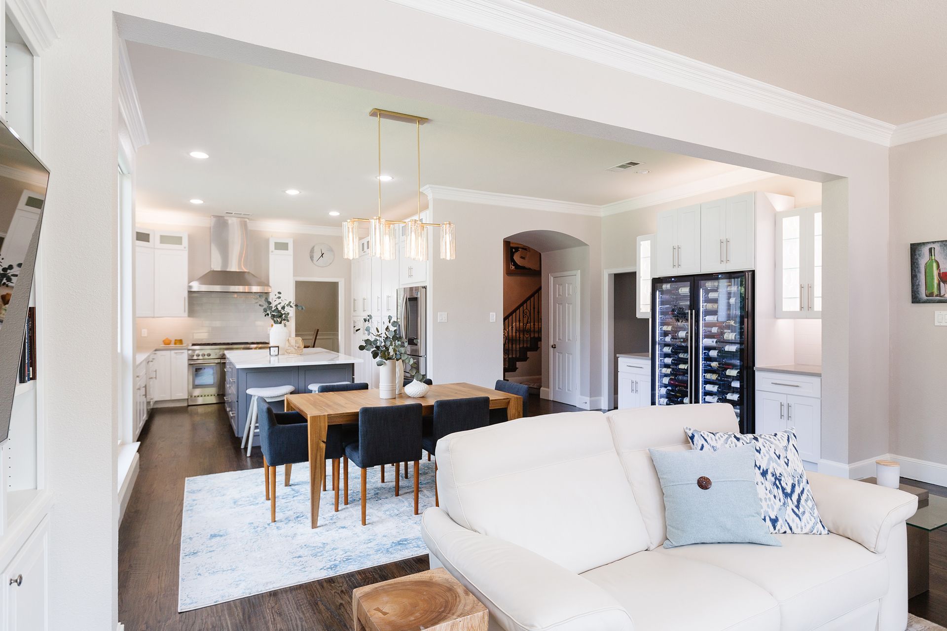 Open-concept living space with kitchen, dining table, and white sofa; neutral tones.