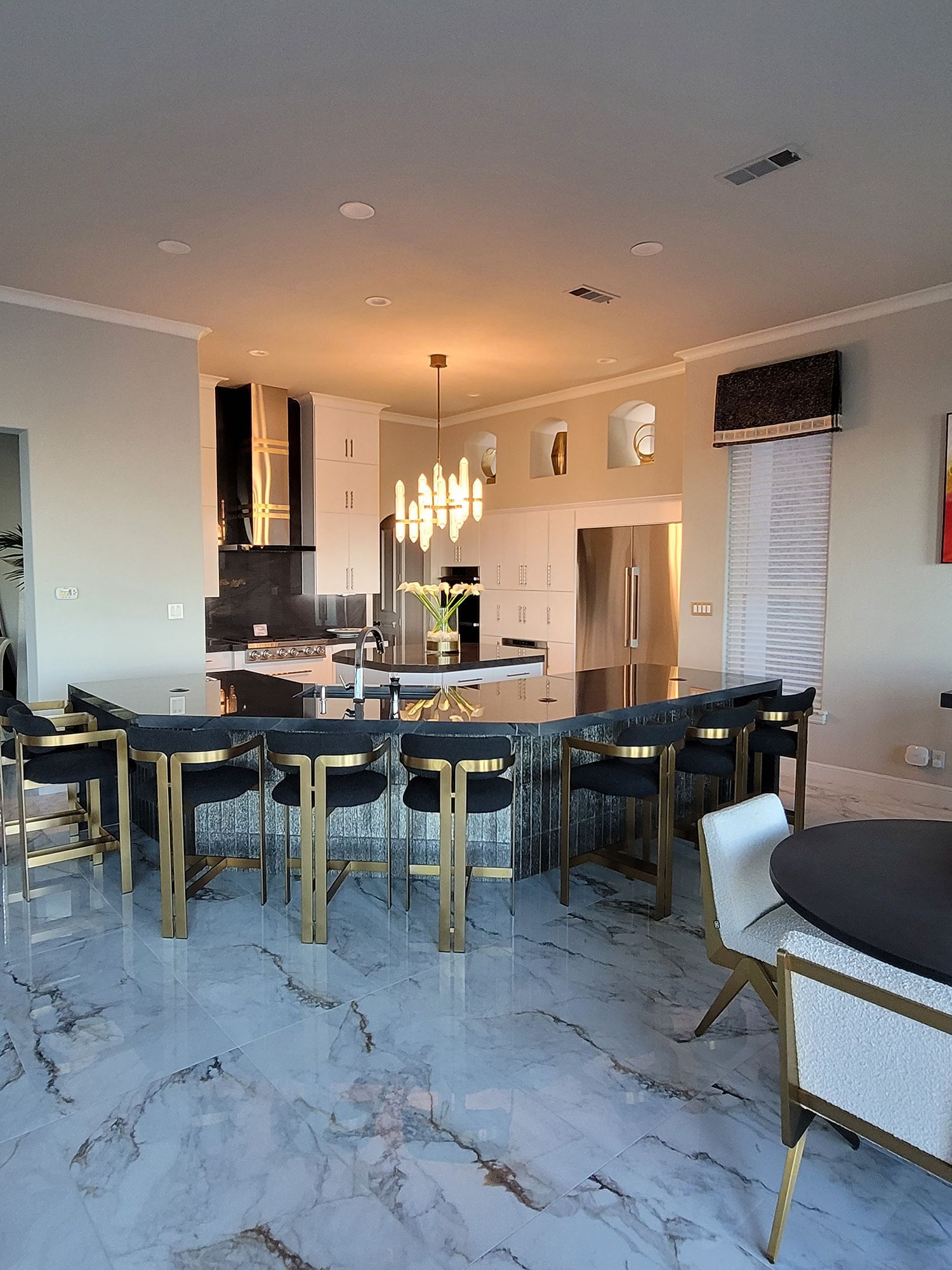 Modern kitchen with a large island, marble floors, and bar stools.
