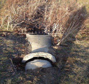 A concrete pipe is sitting in the middle of a grassy field.