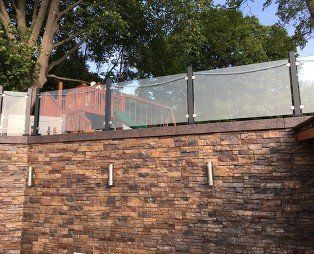 A brick wall with a glass railing on top of it.