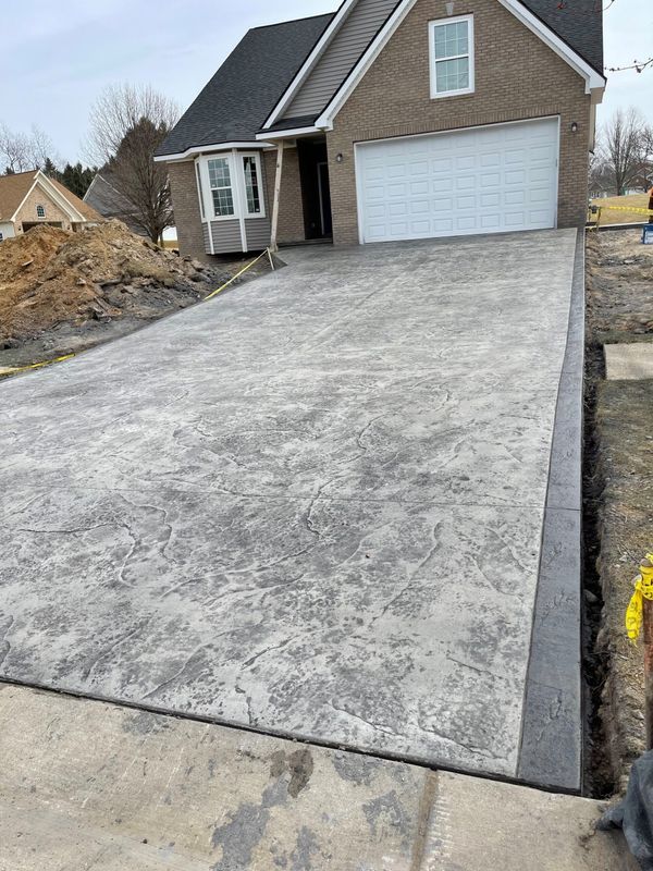 A concrete driveway leading to a house with a garage door.