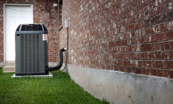 An air conditioner is attached to the side of a brick building.