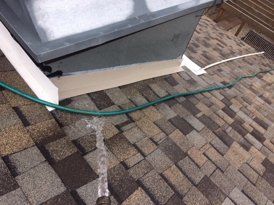 A person is spraying water on a roof with a hose.
