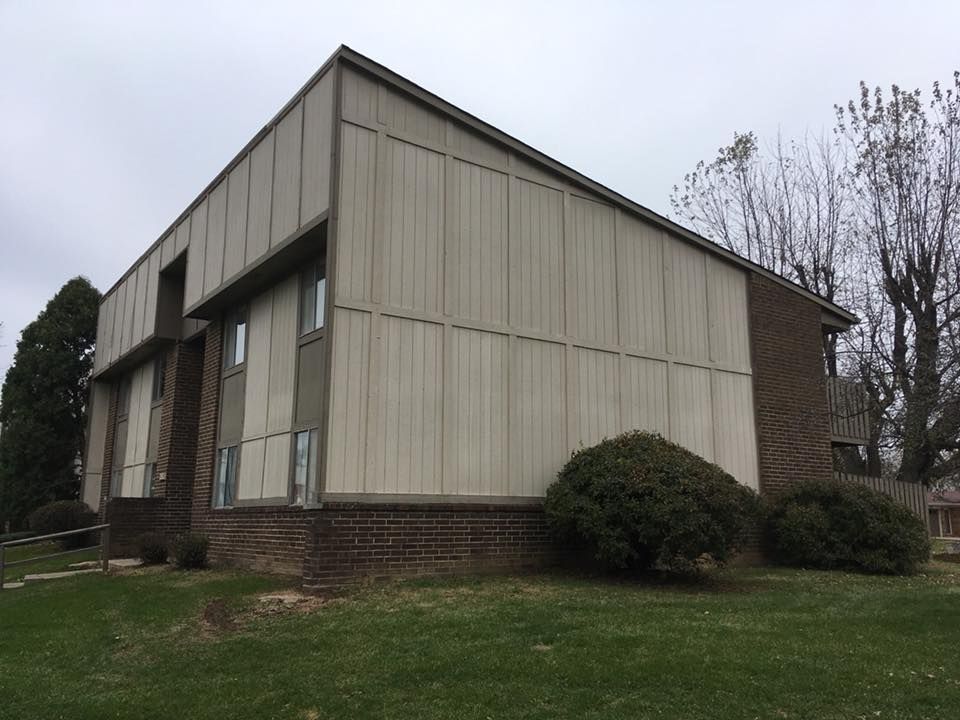 A large building with a lot of windows is sitting on top of a lush green field.