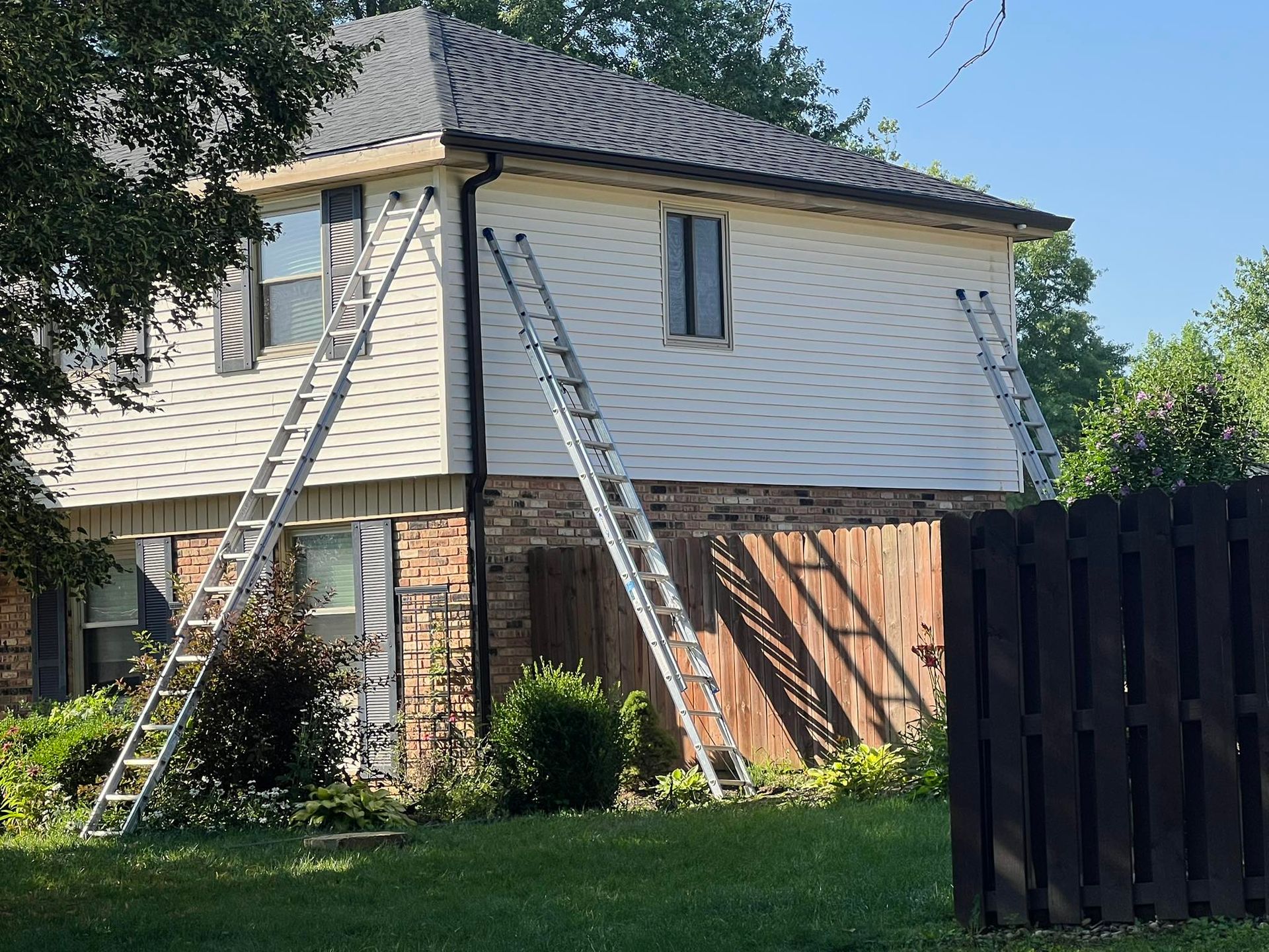 Two ladders are sitting on the side of a house.