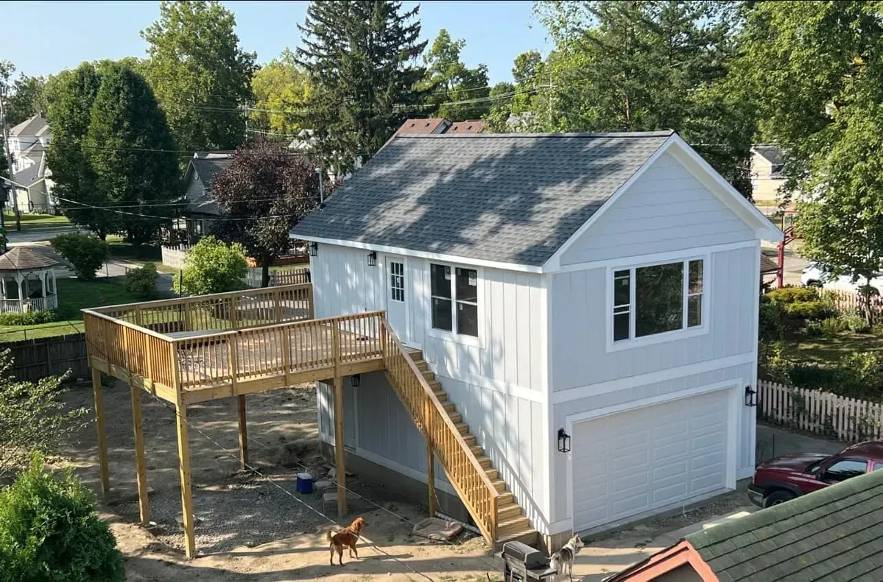 A white house with a wooden deck and stairs.