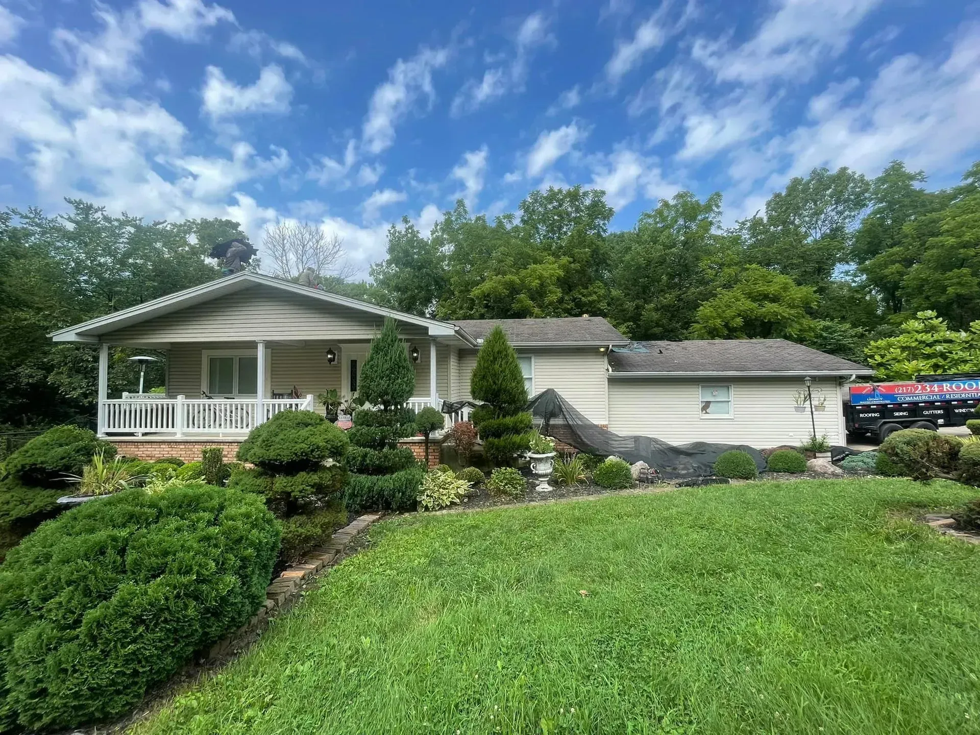 A white house with a porch and a large lawn in front of it.
