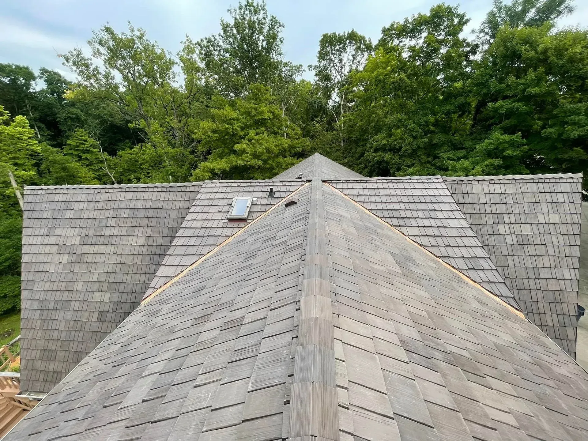 A wooden roof with a skylight and trees in the background.