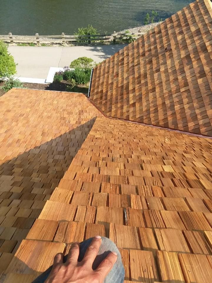 A person is looking down at a wooden roof with a river in the background.