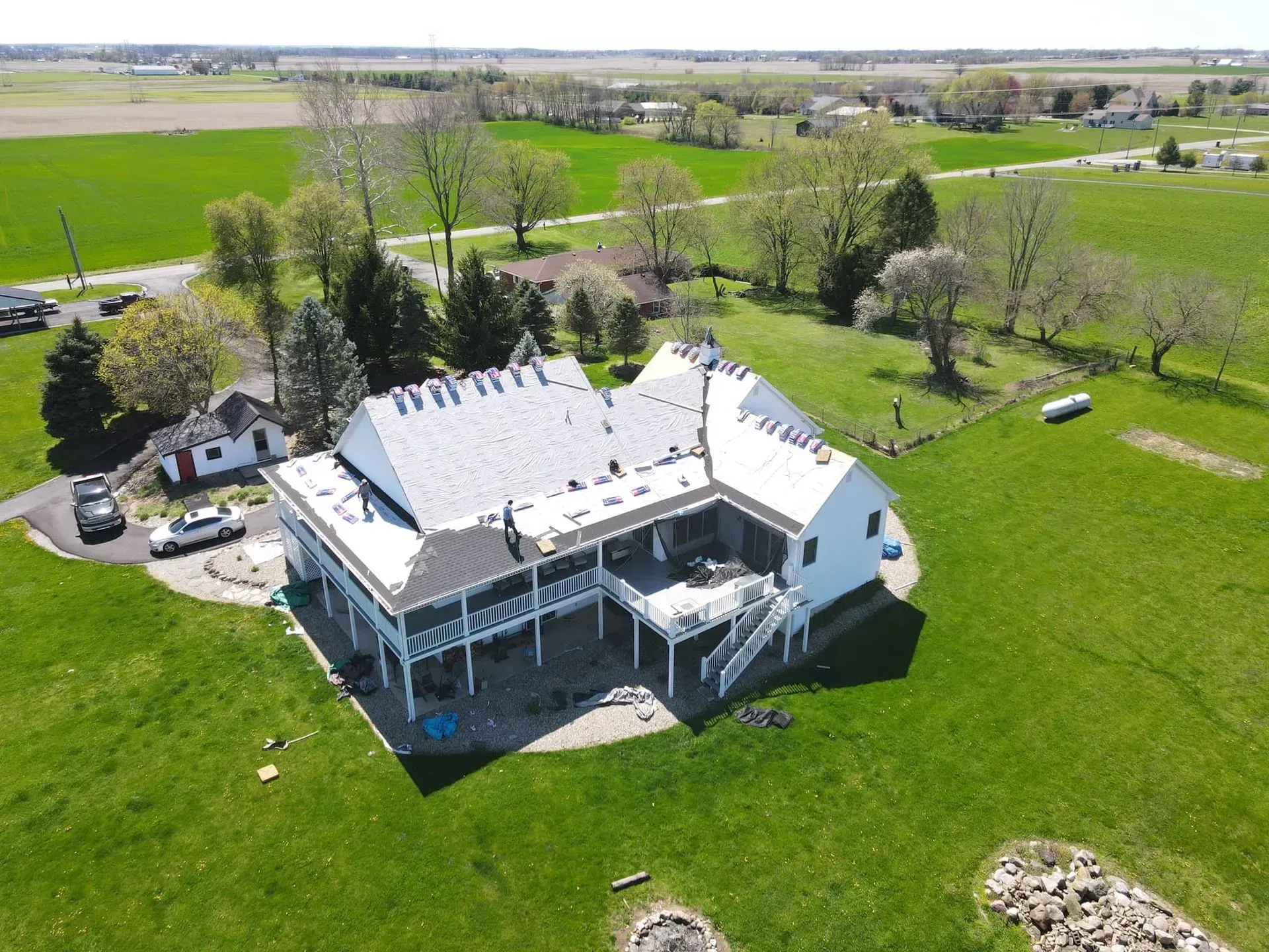 An aerial view of a large white house in the middle of a grassy field.