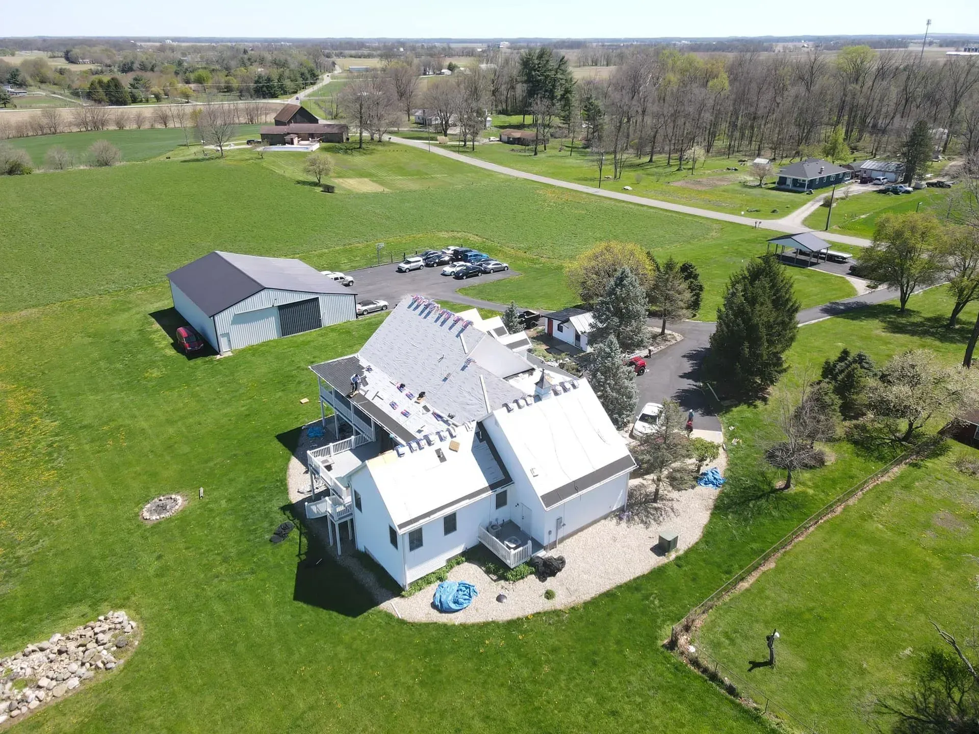 An aerial view of a large white house in the middle of a lush green field.
