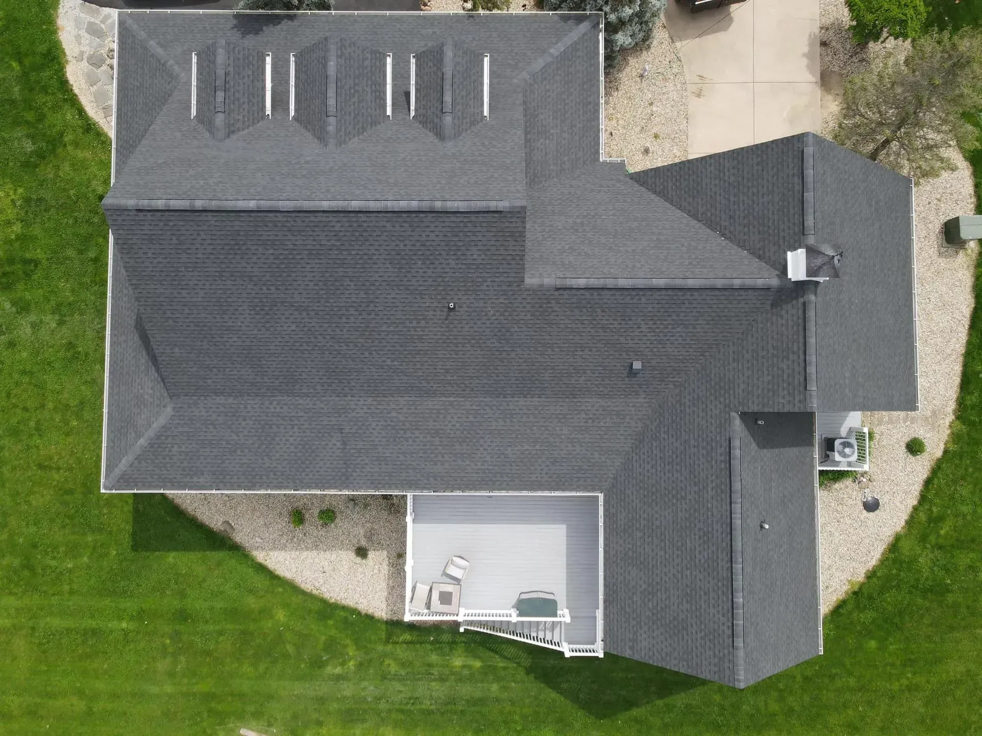 An aerial view of a large house with a gray roof surrounded by grass.