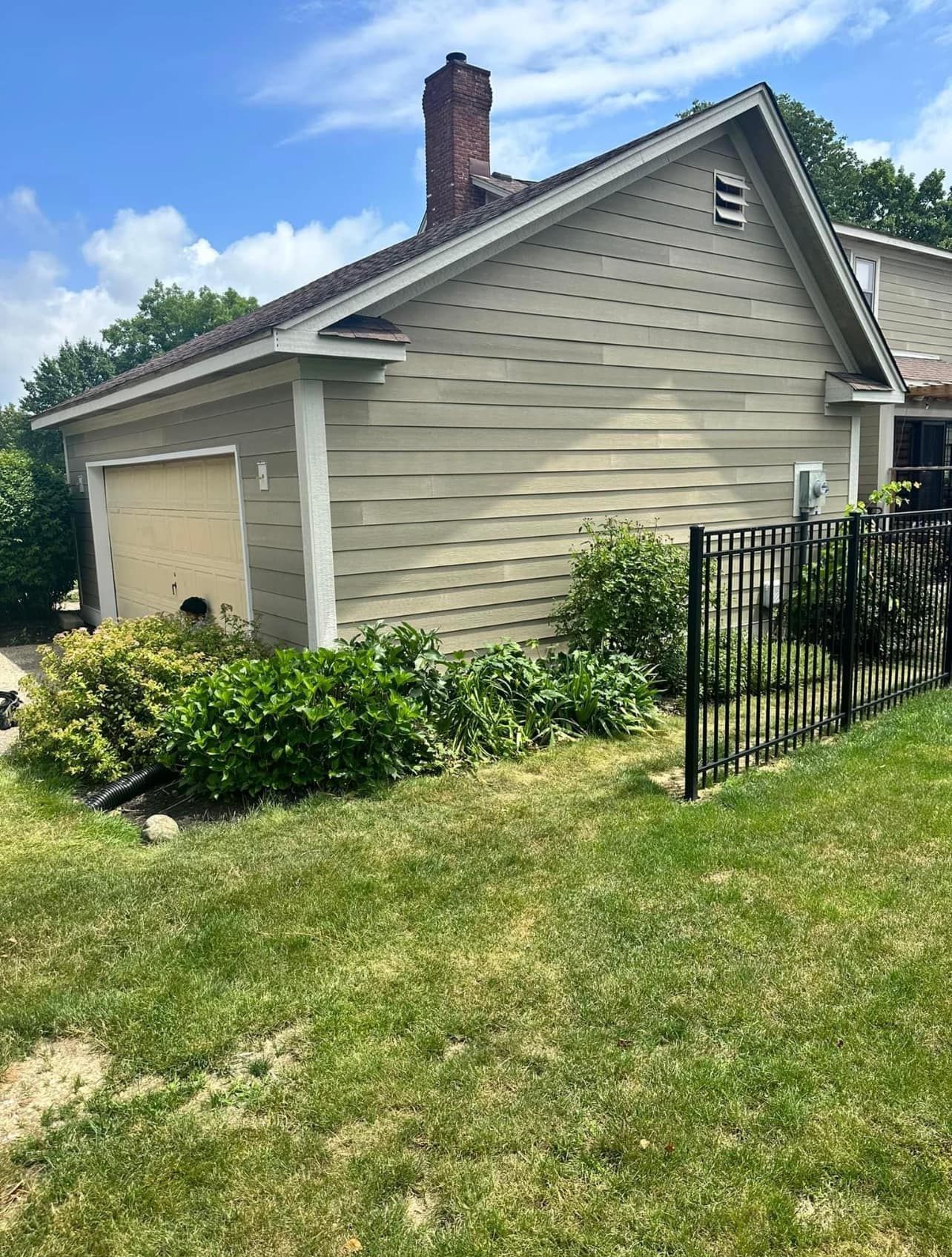 A house with a garage and a fence in front of it.