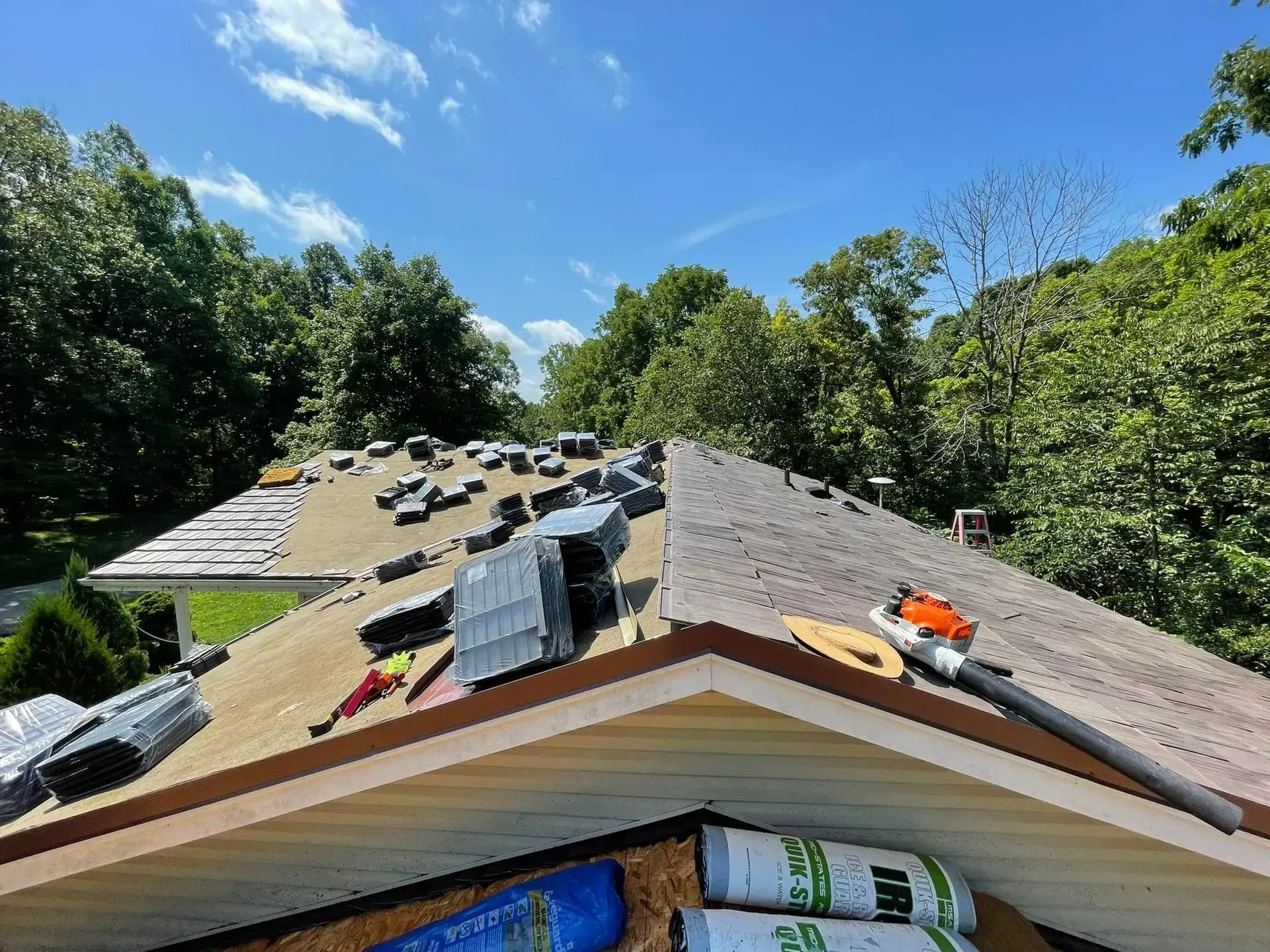 The roof of a house is being repaired on a sunny day.