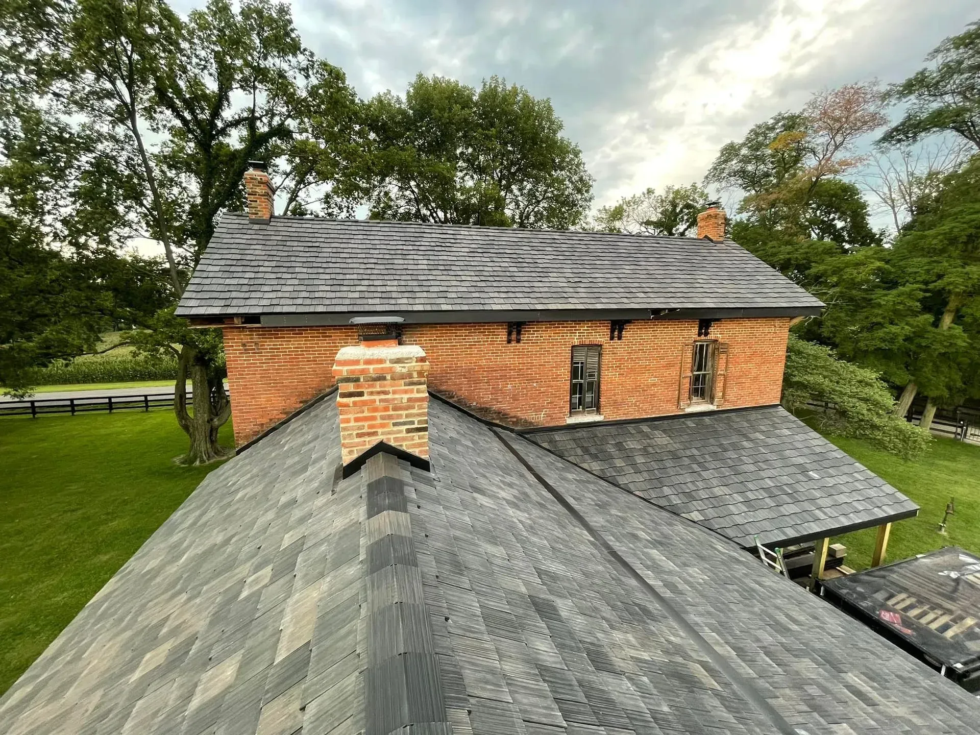 A brick house with a black roof and a chimney.